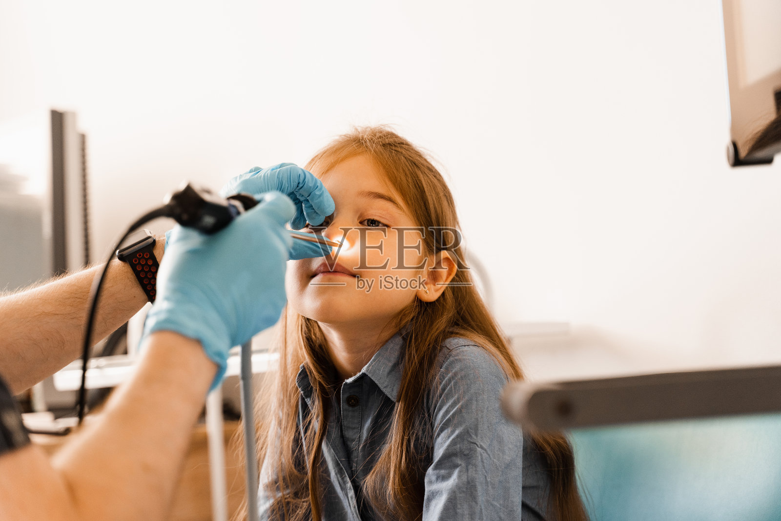 儿童鼻内窥镜。鼻镜检查。耳鼻喉科医生用前照灯治疗鼻儿童患者。照片摄影图片