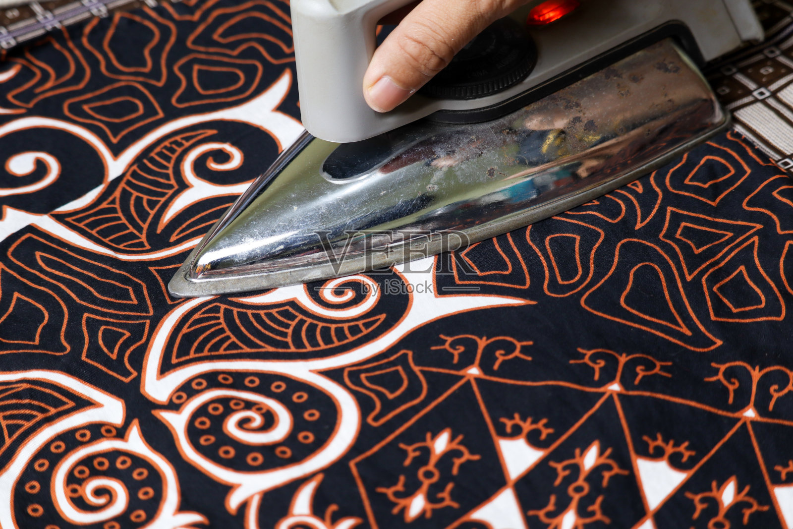 有选择地集中在熨烫印尼蜡染织物的手上照片摄影图片