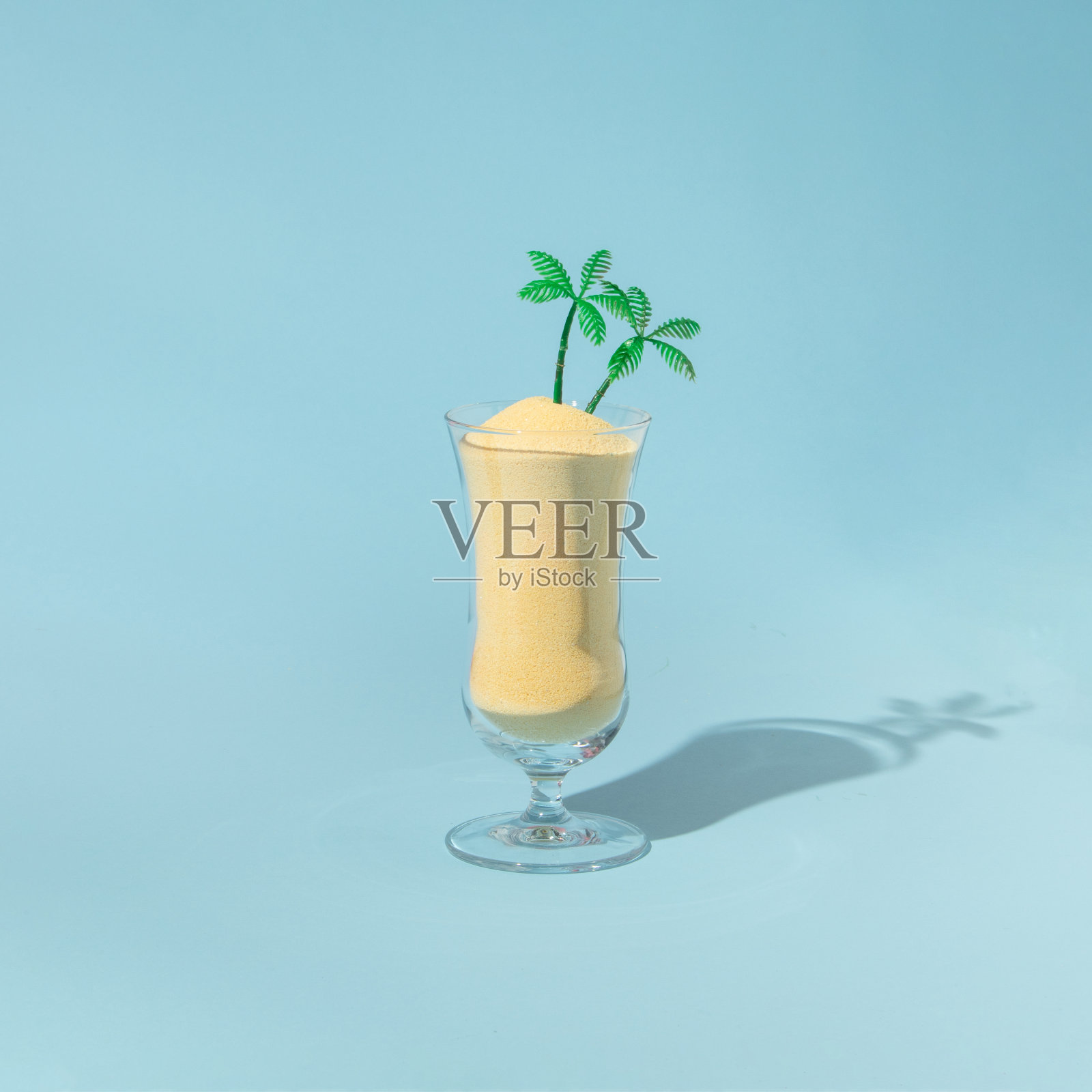 夏季热带创意布局与鹦鹉玻璃与沙子和棕榈树的雕像在柔和的蓝色背景。80、90年代复古时尚美学夏日概念。简约的波普艺术茶点概念。照片摄影图片