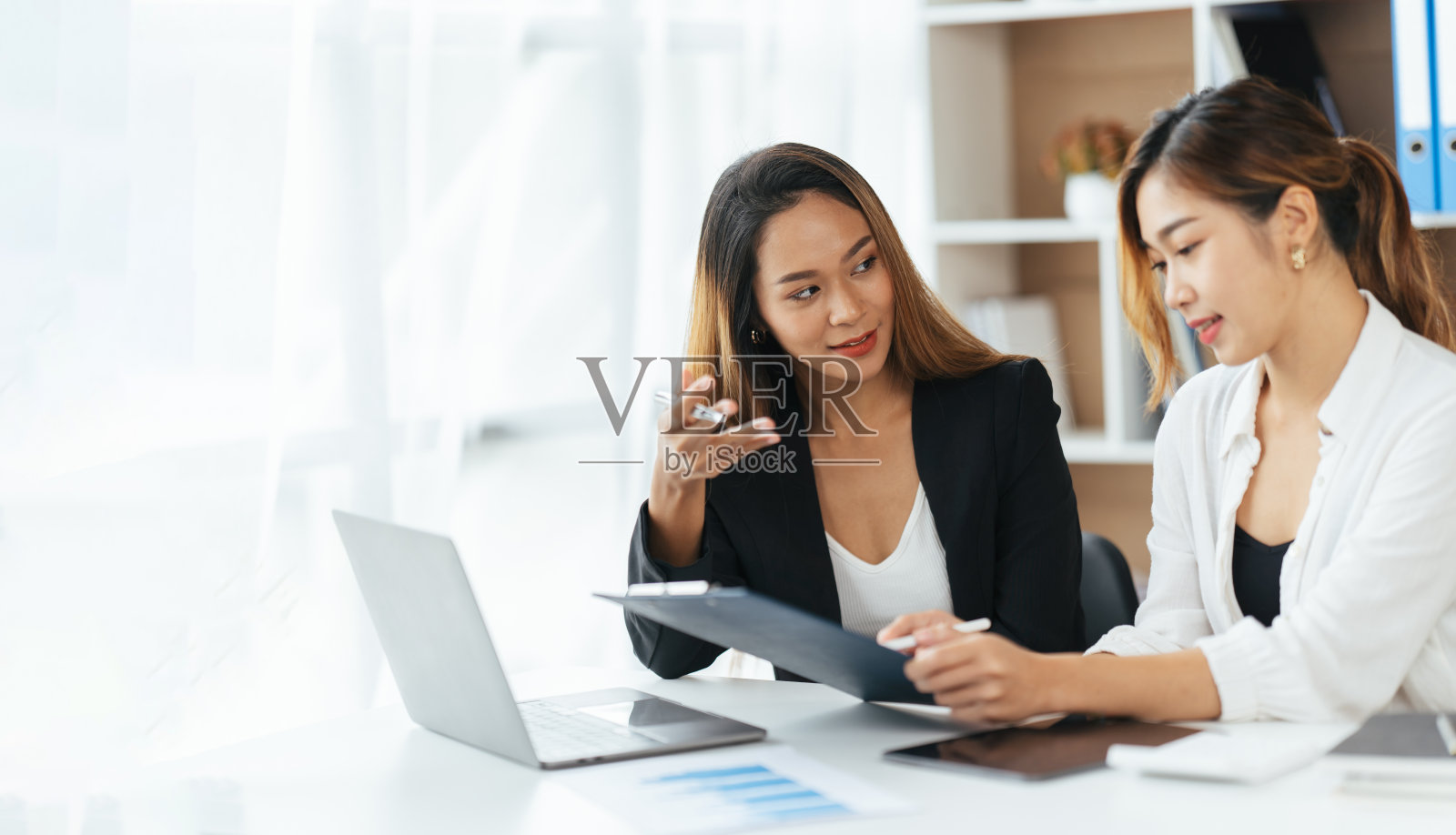 年轻快乐的女商人在现代办公室与同事使用电脑。两个女同事在办公室一起工作。照片摄影图片