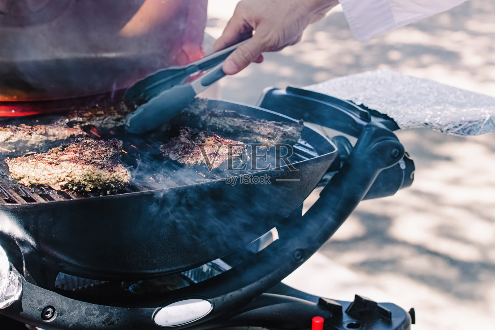 一个人在烤架上烧肉。照片摄影图片