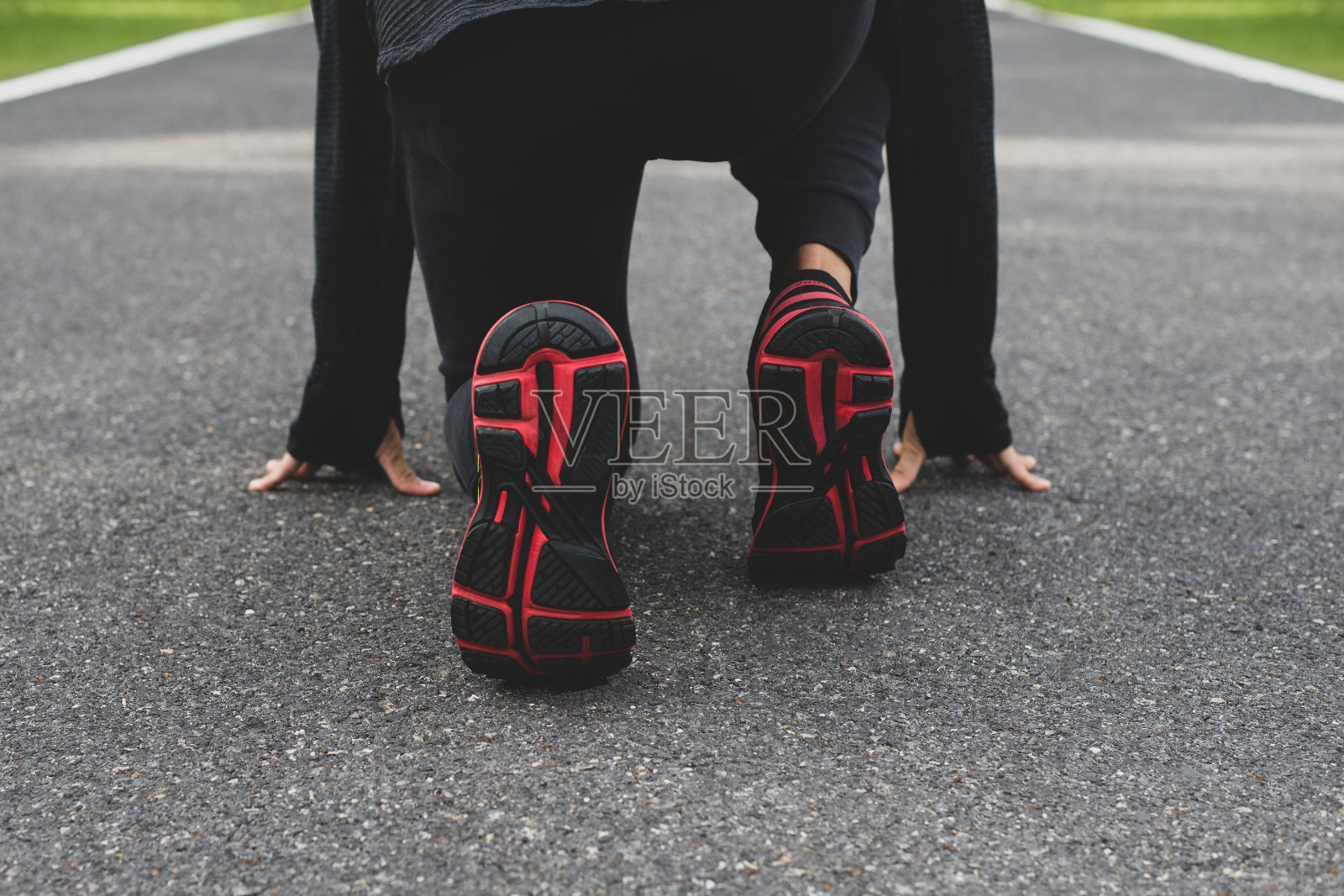 一个穿着黑色运动服的年轻跑步者正准备在公园里跑步。照片摄影图片