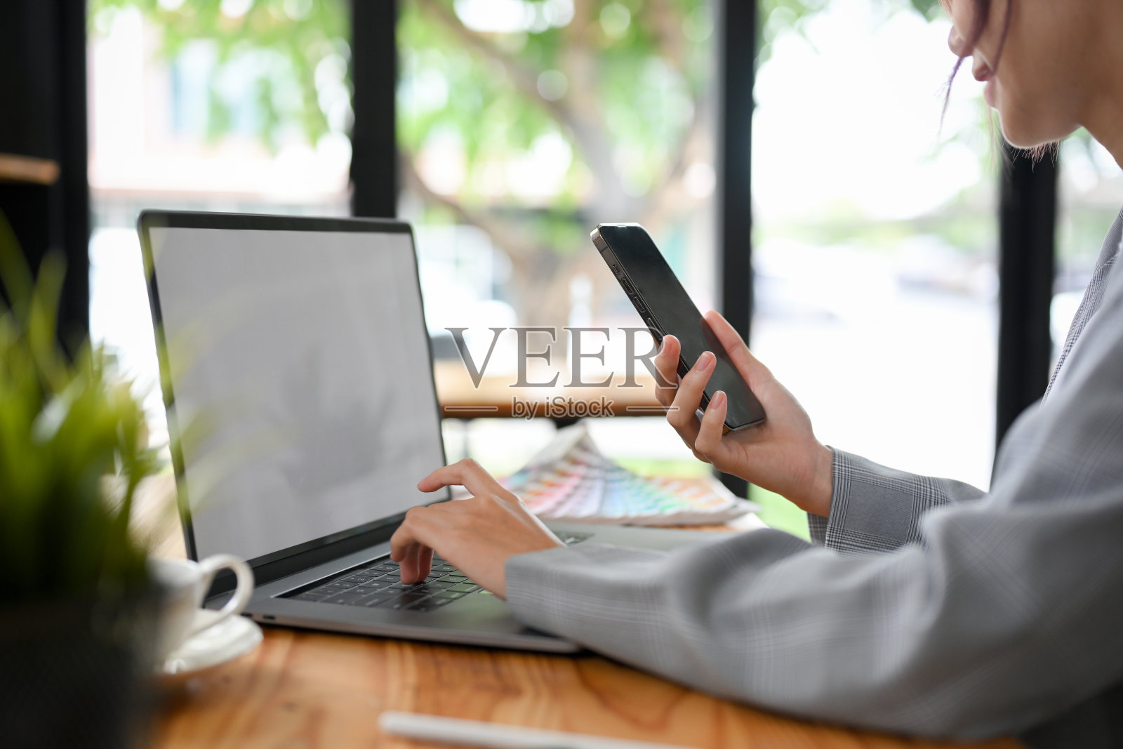 一位在餐桌上使用便携式笔记本电脑和智能手机的女商人照片摄影图片