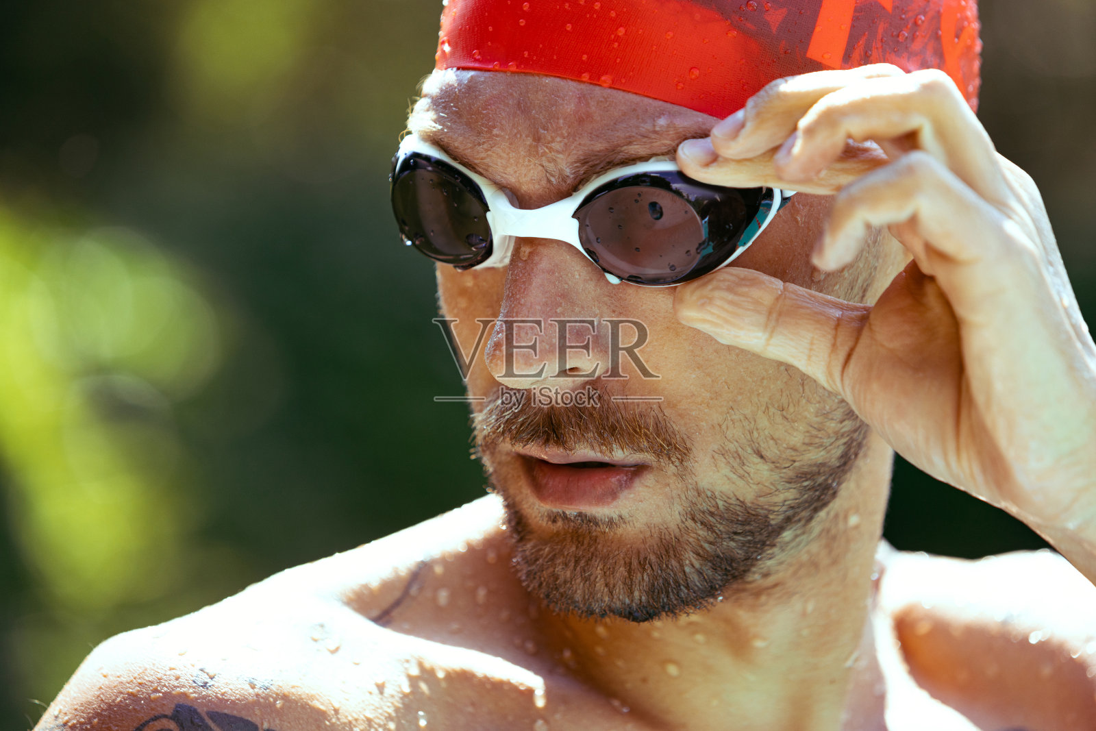 特写年轻英俊的男子,专业游泳运动员在护目镜和游泳帽准备游泳,在户外。运动,动力,能量,风格,爱好概念。照片摄影图片