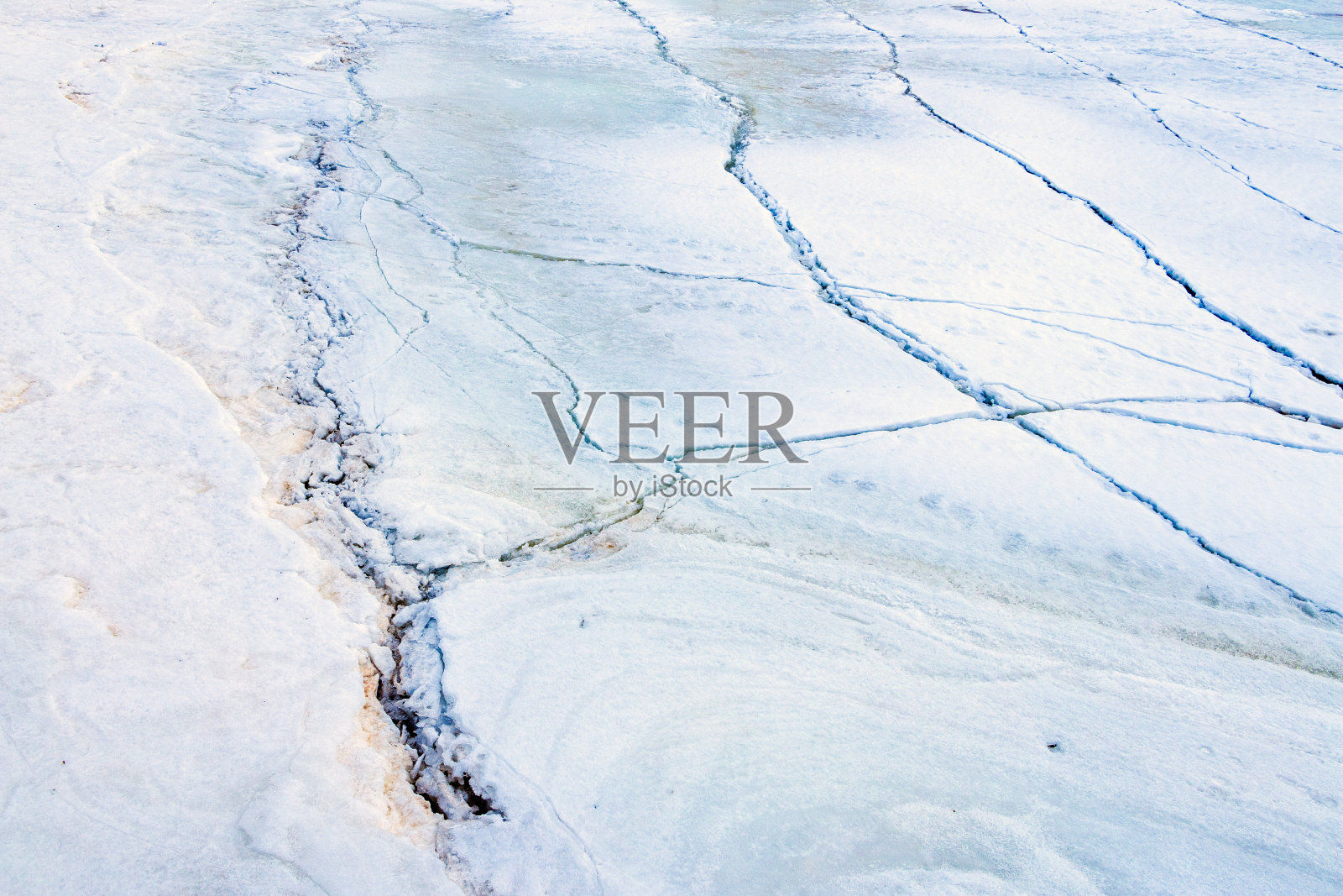 冬天结冰的河流表面厚冰上的裂缝,被雪和沙子磨成粉末,晶莹剔透的冰晶。照片摄影图片