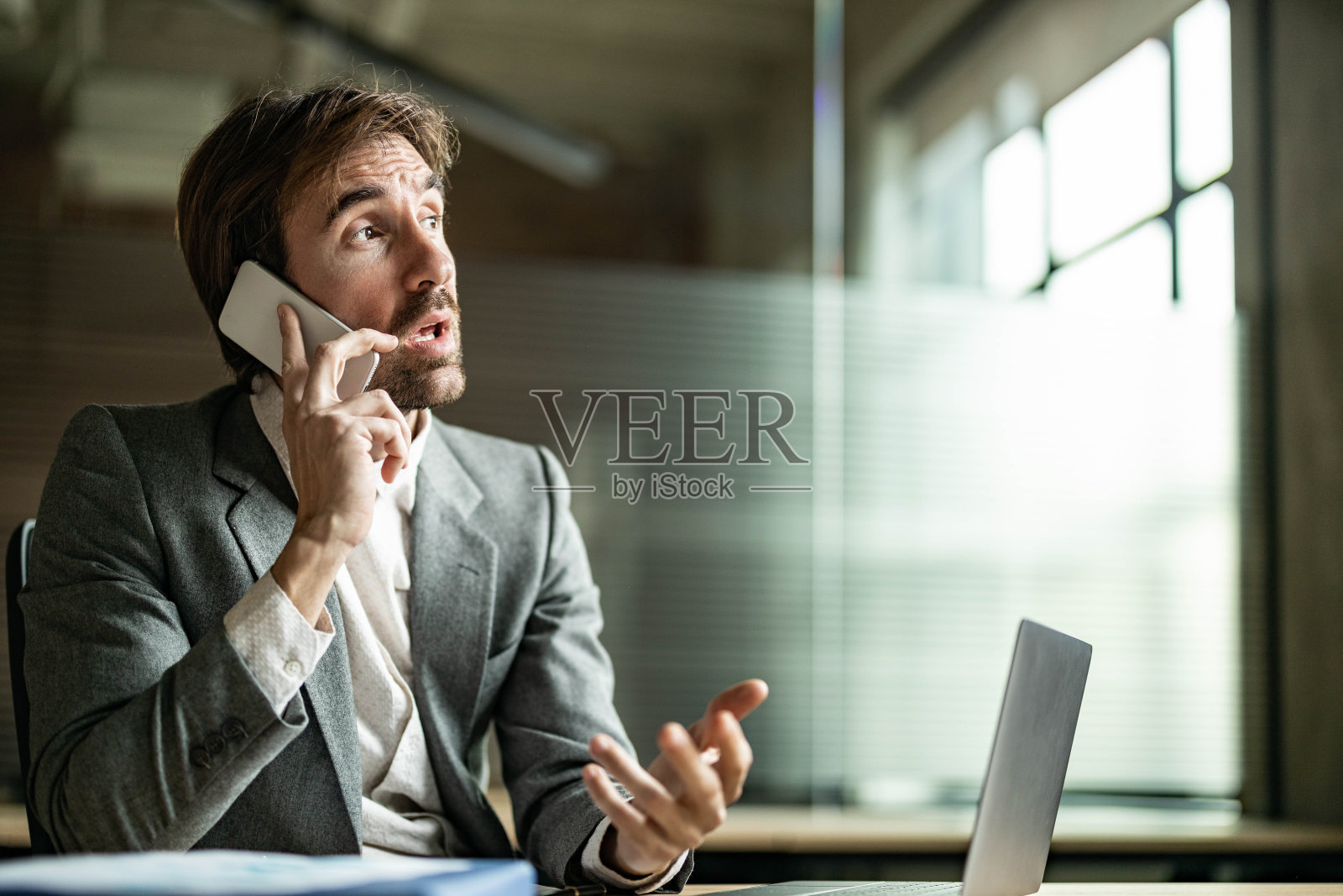 年轻的商人在办公室打手机。照片摄影图片