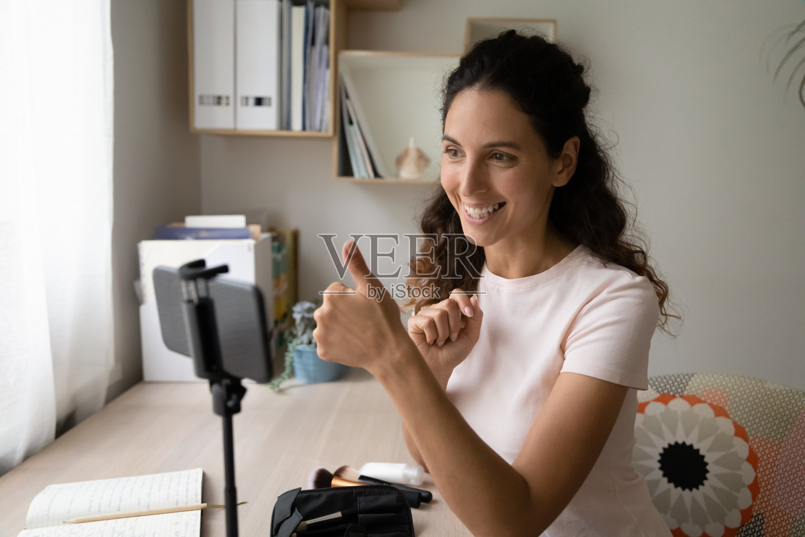 女子在智能手机上录制视频博客,显示竖起大拇指的手势照片摄影图片