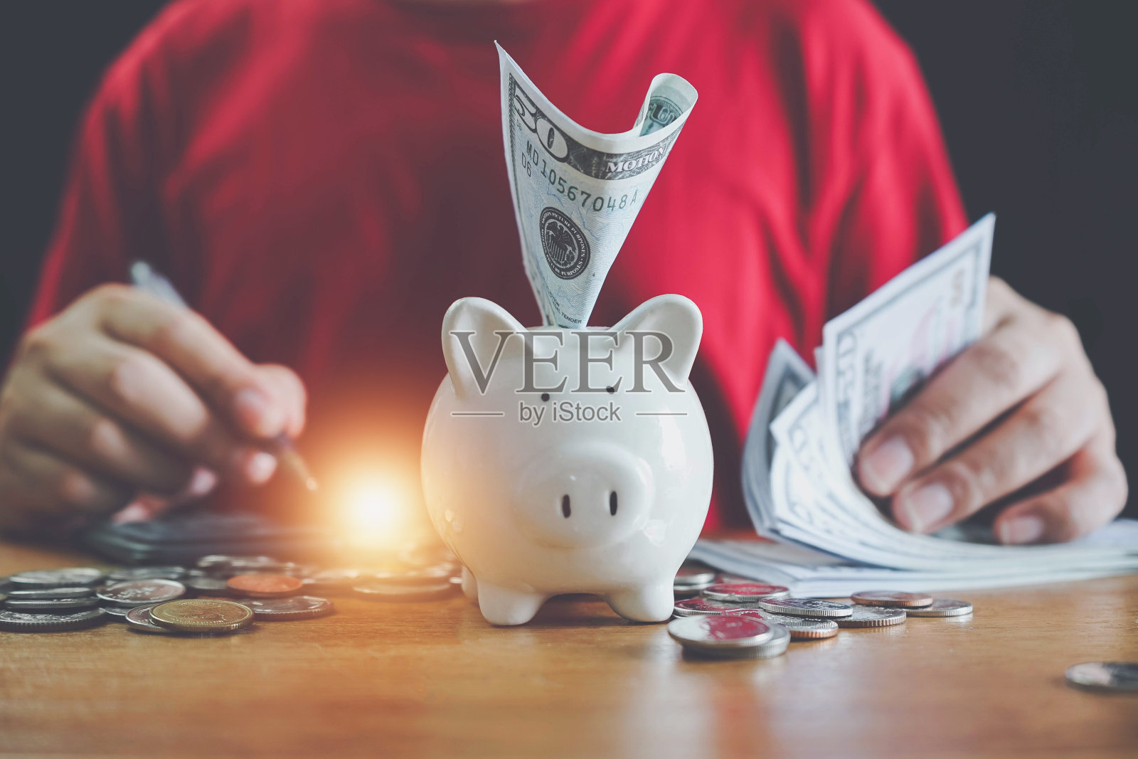 节能省钱的理念。硬币堆放在书桌上,用于规划货币理财。储蓄和金融账户的概念。木桌上放有猪储蓄罐的硬币,省钱。照片摄影图片