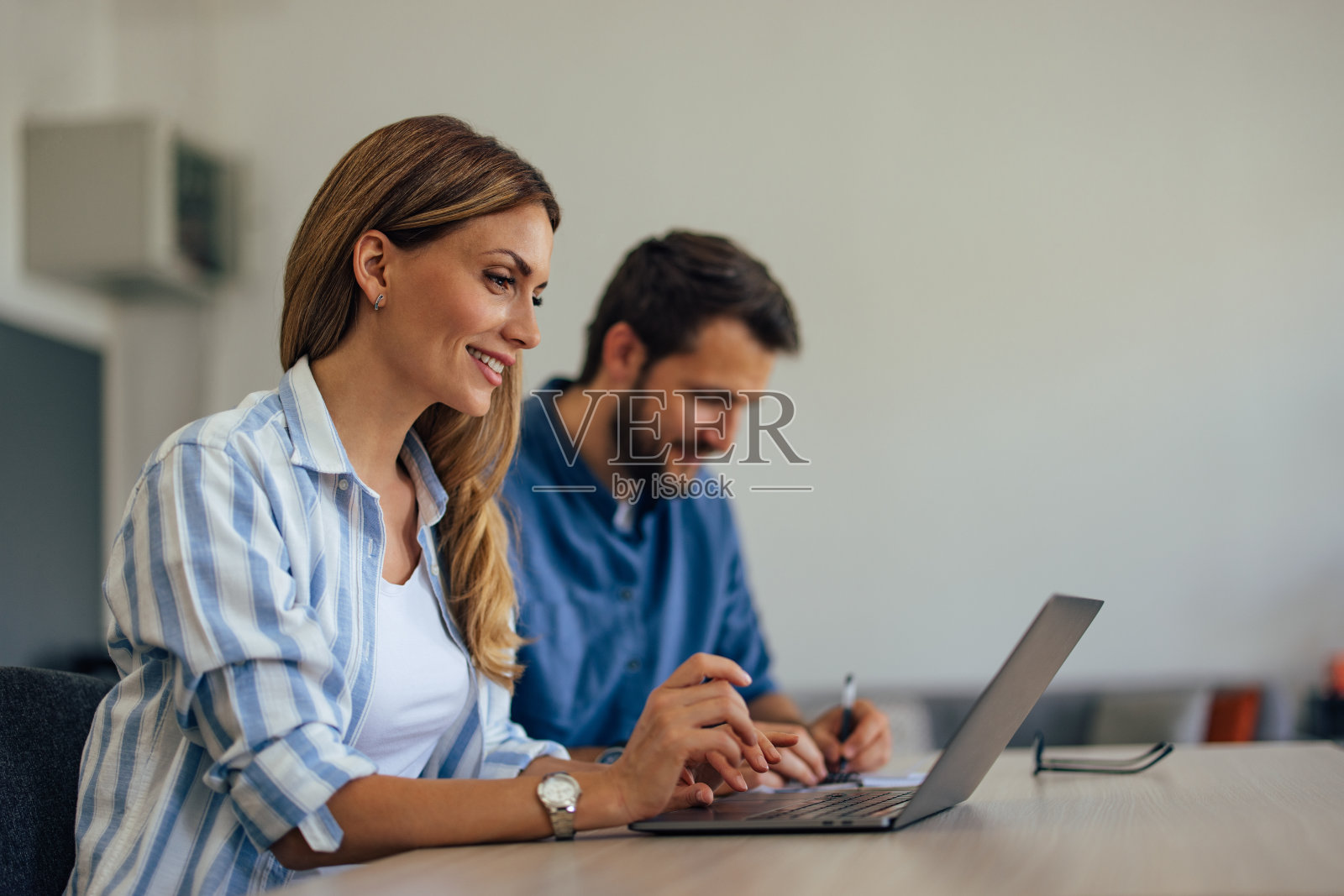 盯着那个女人,在电脑前工作,商人在后台。照片摄影图片