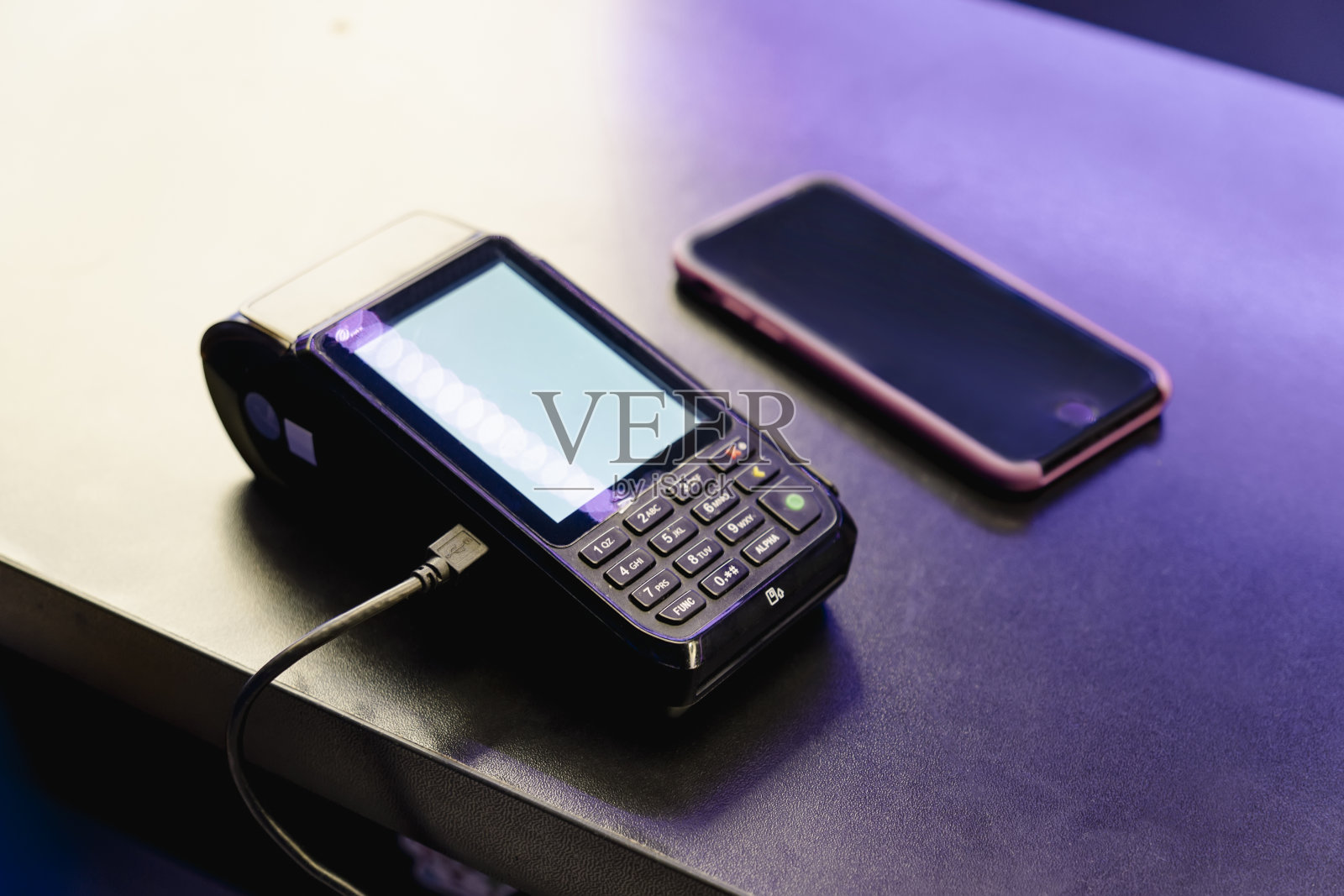 支付终端和智能手机放在酒吧的桌子上。付款通过wi - fi。近场通信,NFC。pos终端上的文字和设计的空白屏幕照片摄影图片