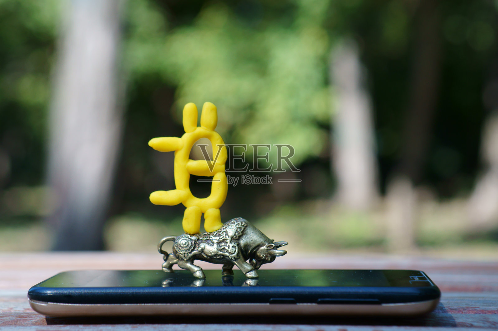 一个比特币小雕像和一个手机上的金属牛。照片摄影图片