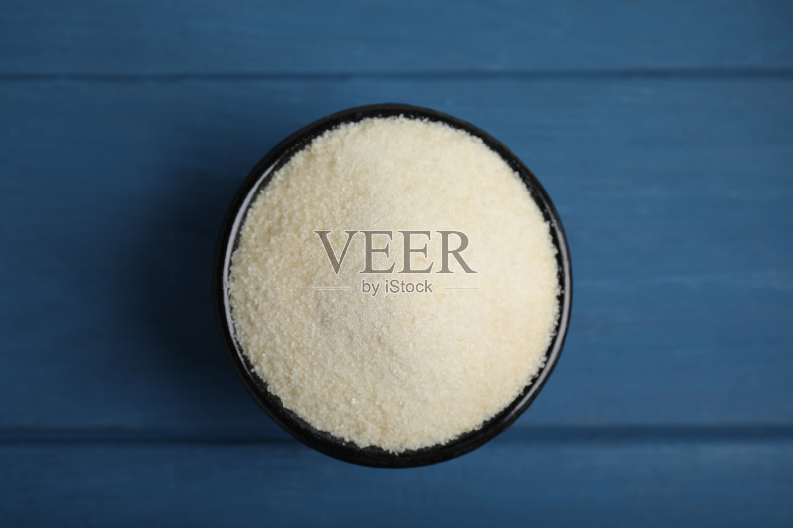 蓝色木桌碗中的明胶粉,俯视图照片摄影图片