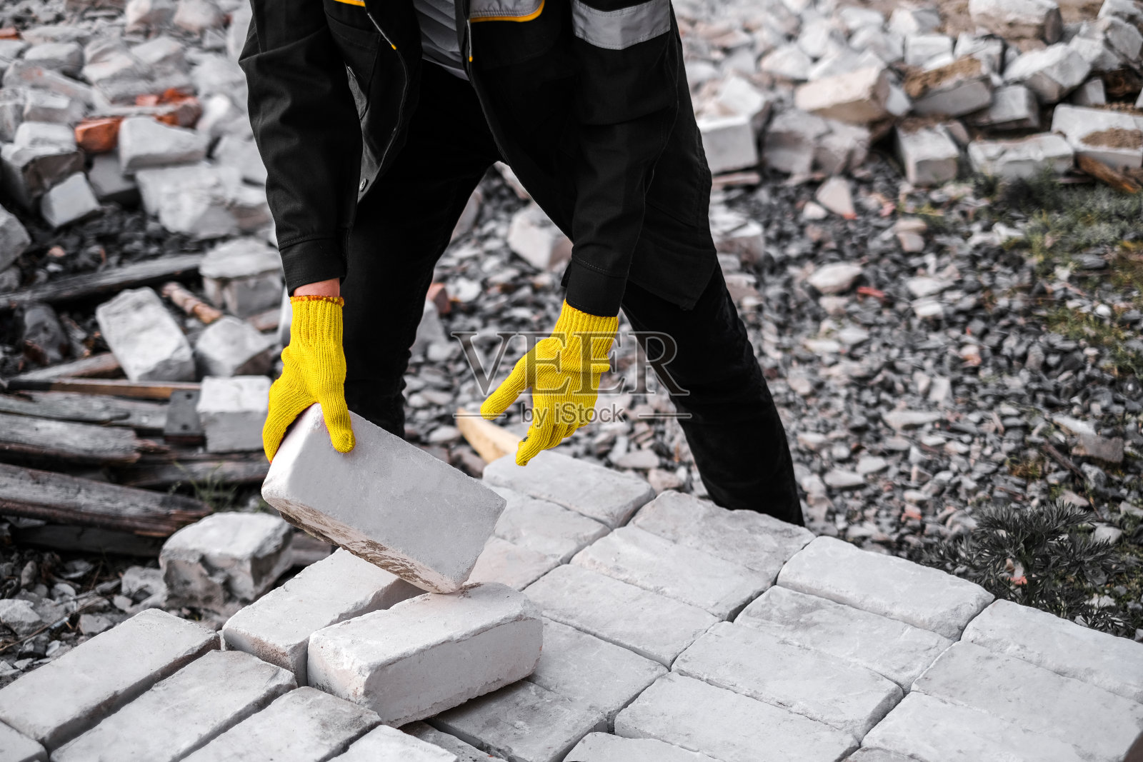 一名戴着安全帽和防护手套的男建筑工人在建筑工地卸砖照片摄影图片