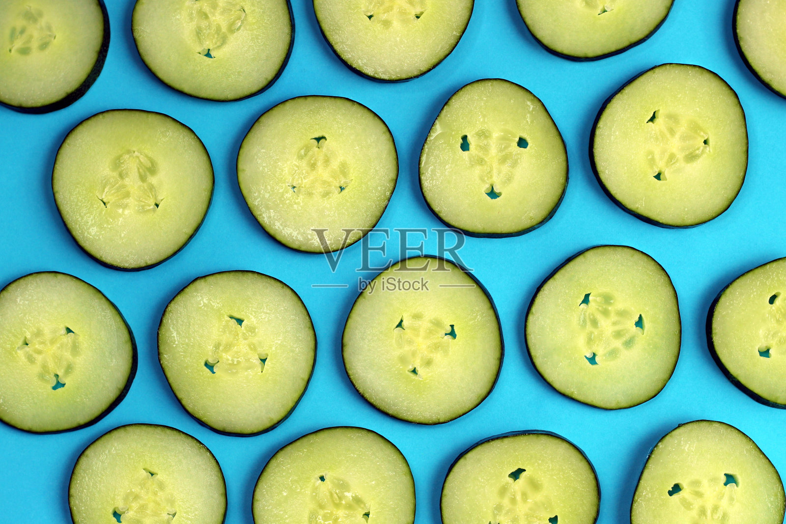 蓝色背景上黄瓜片的纹理。照片摄影图片