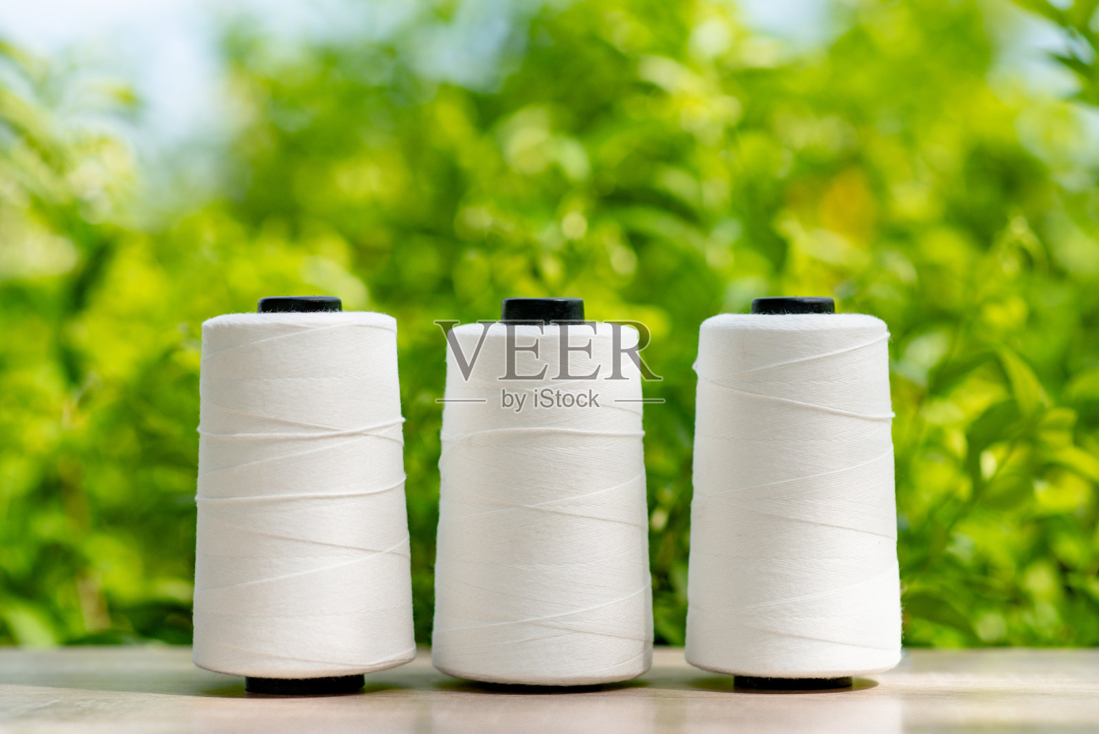 原料白色涤纶FDY纱芯与绿色模糊背景照片摄影图片