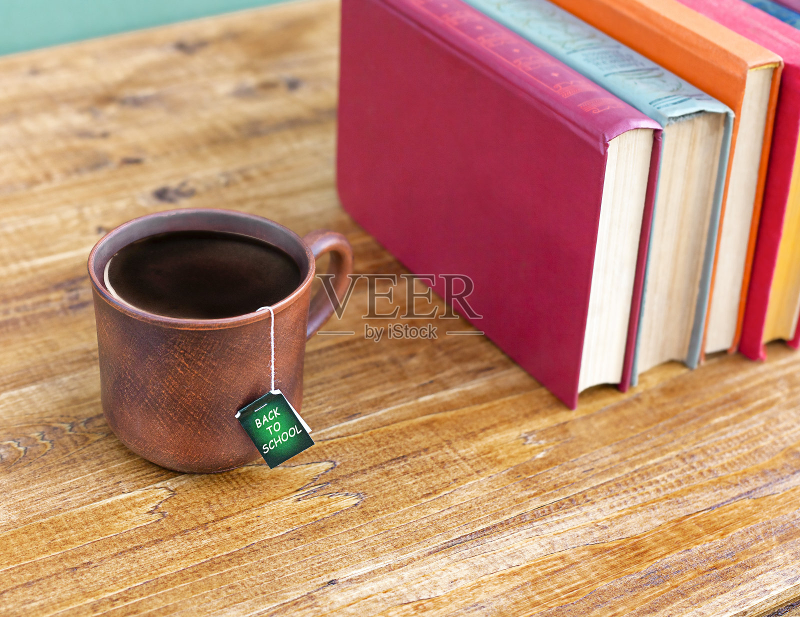 木桌上放着茶水和一叠书照片摄影图片