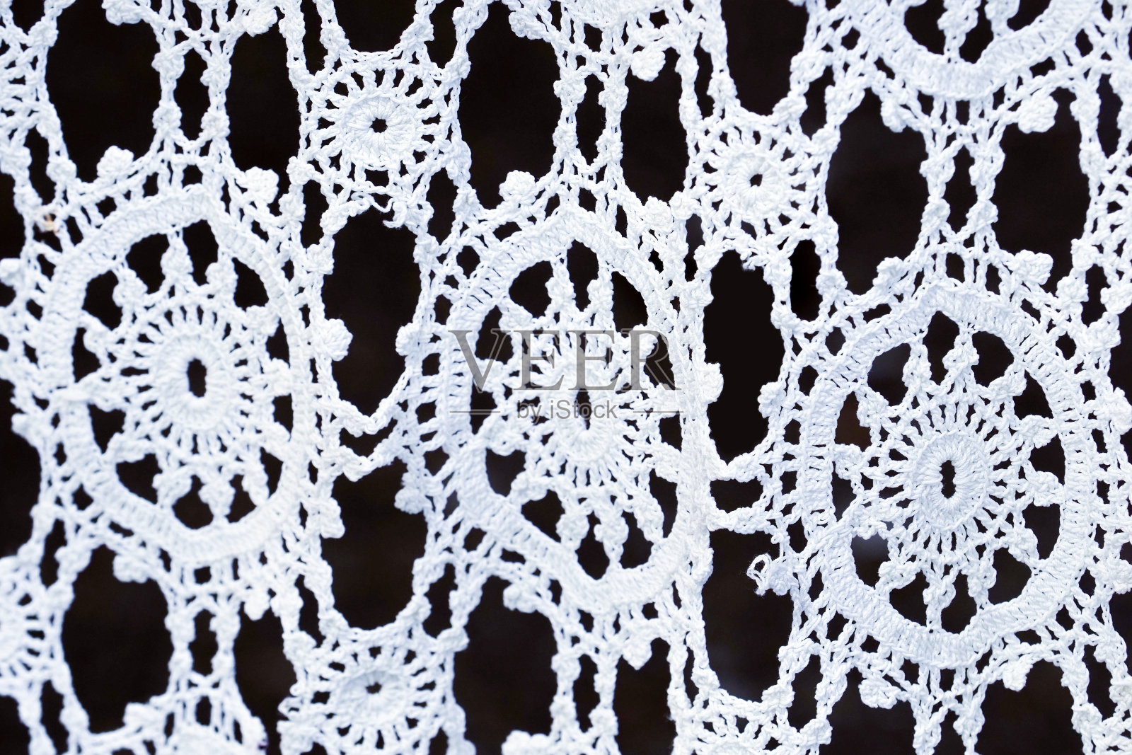 钩针白色花边在黑暗的背景,工艺,手工。花边的背景照片摄影图片