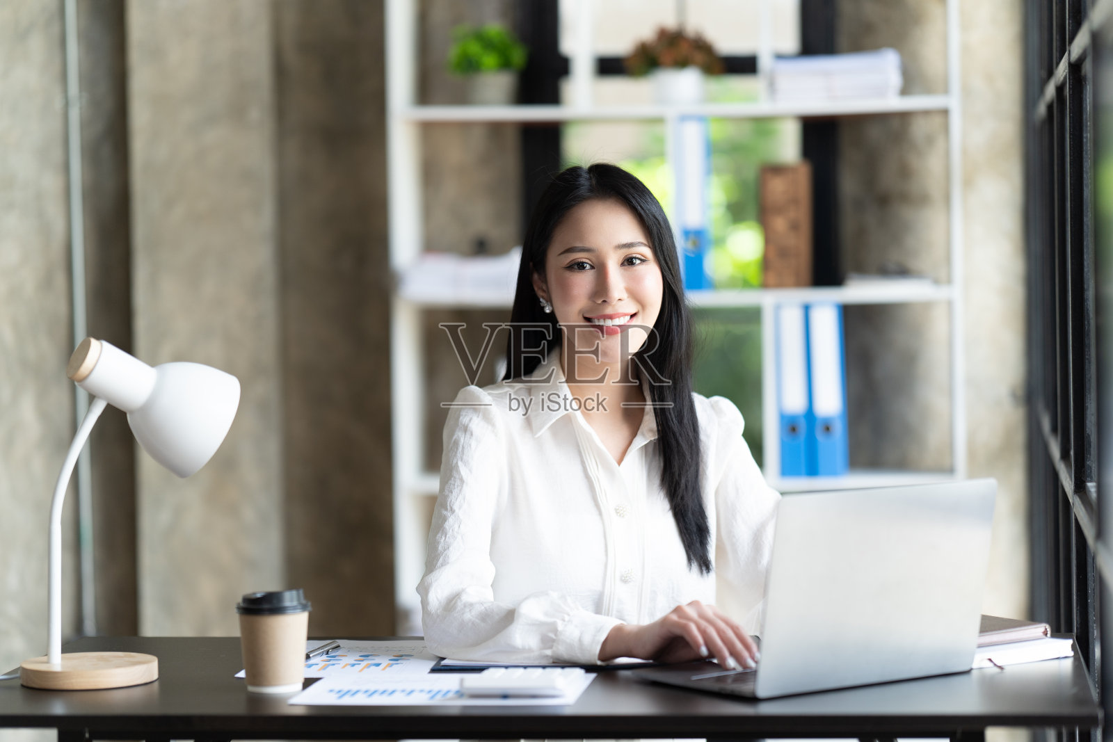 一位在办公室用笔记本电脑工作的亚洲女性。商业金融的概念。照片摄影图片