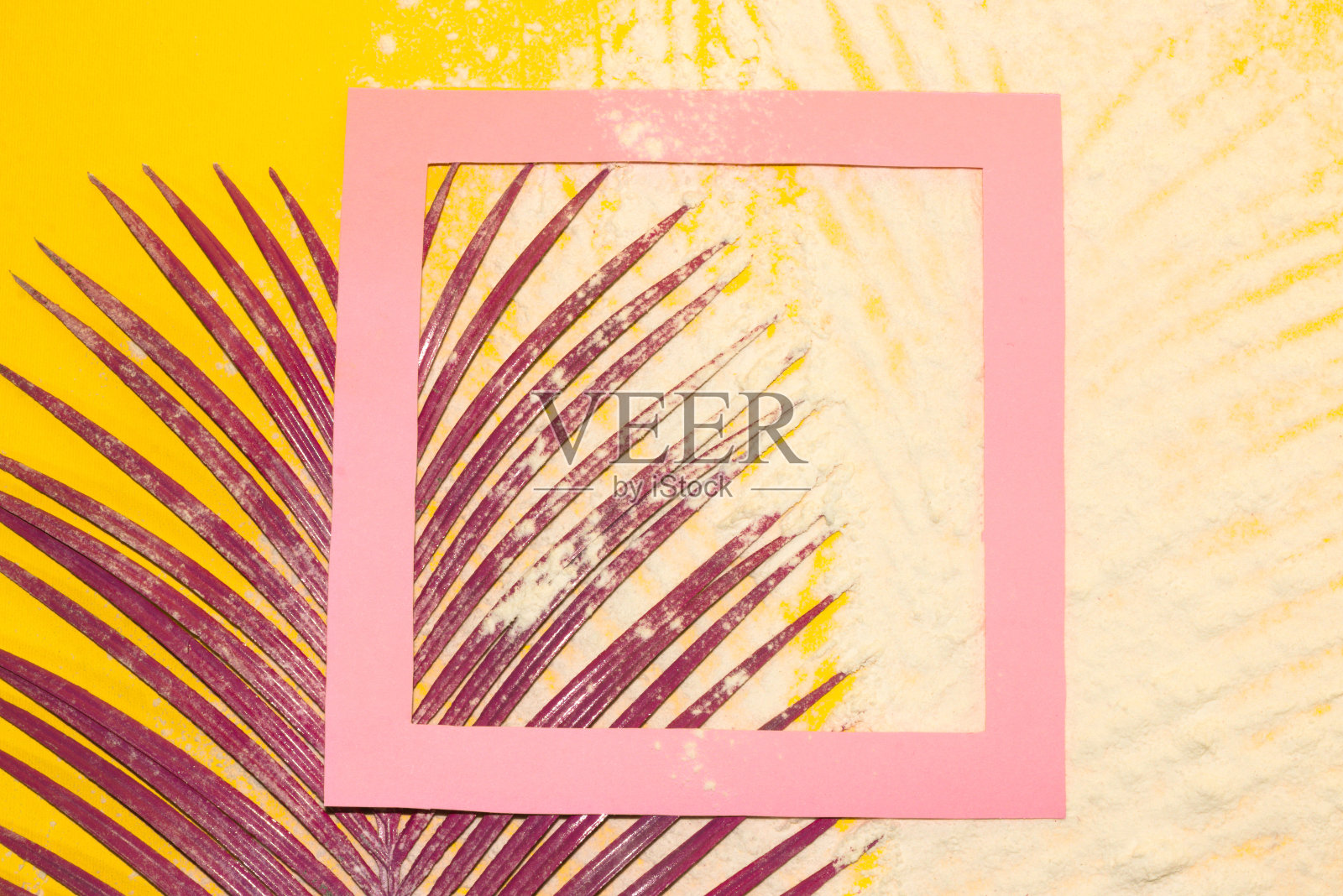 黄色背景以沙滩沙和粉色框架作为复制空间,角落的粉色棕榈叶,创意现代热带背景照片摄影图片