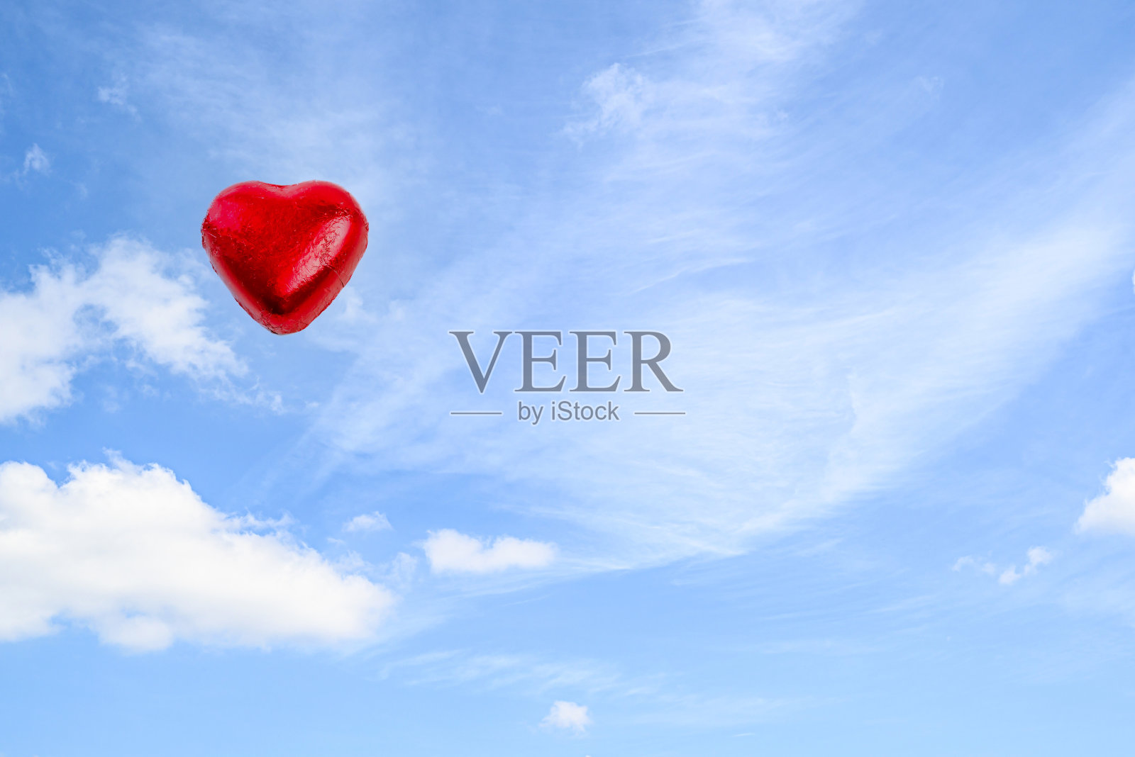 蓝色背景白色云朵上的红色巧克力心照片摄影图片