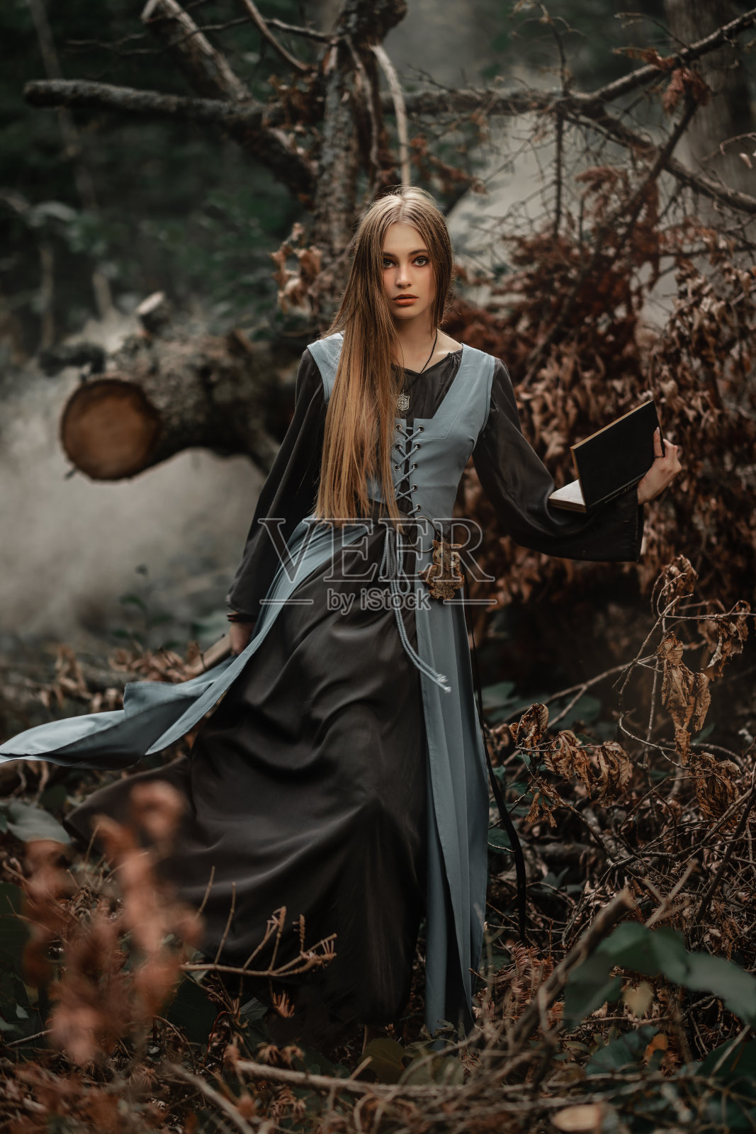 一个神秘的女巫在黑暗的森林中行走照片摄影图片