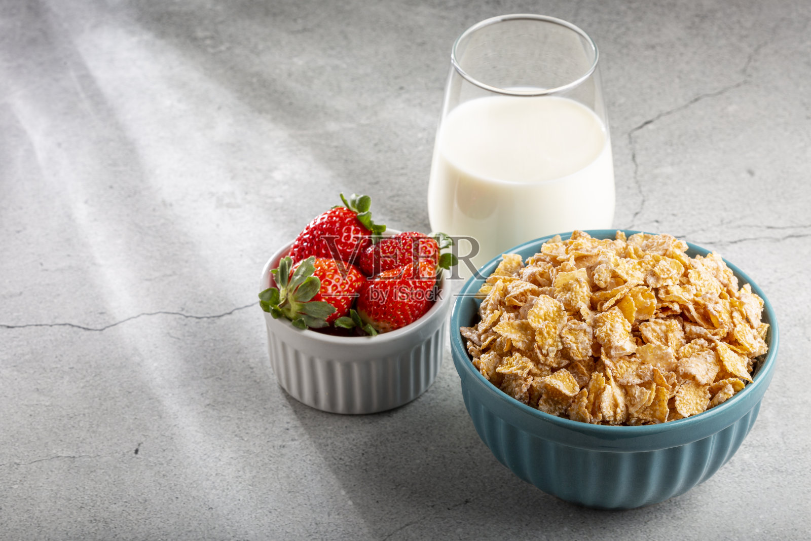 碗里放着玉米片,桌上放着浆果和牛奶。照片摄影图片