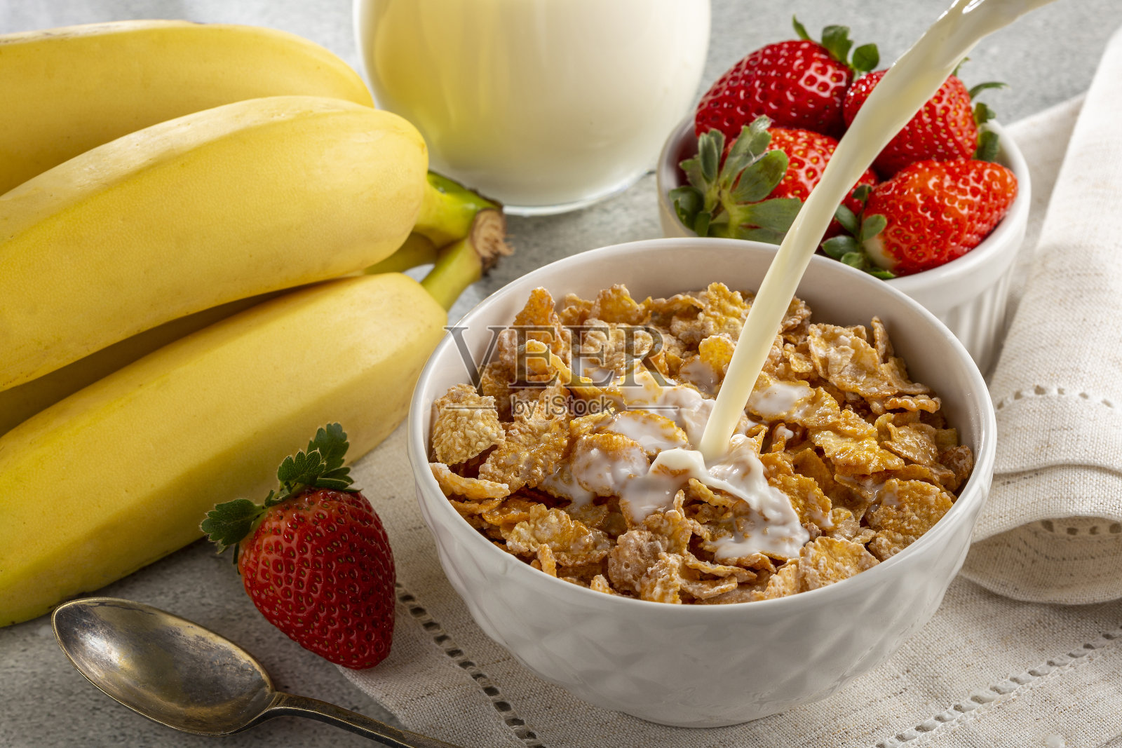 碗里放着玉米片,桌上放着浆果和牛奶。照片摄影图片
