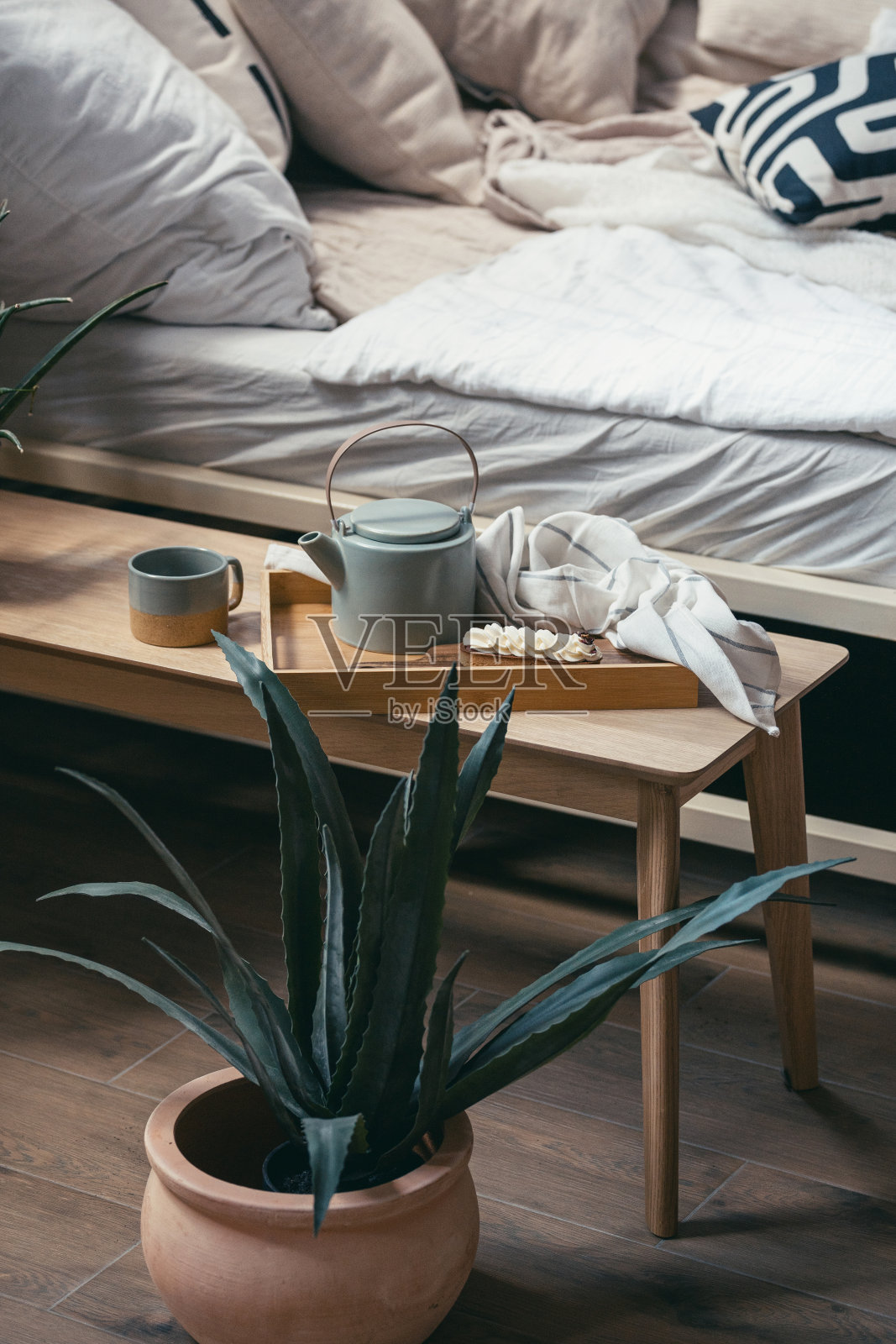 甜点、茶杯和茶壶放在早餐托盘上,靠在床上照片摄影图片