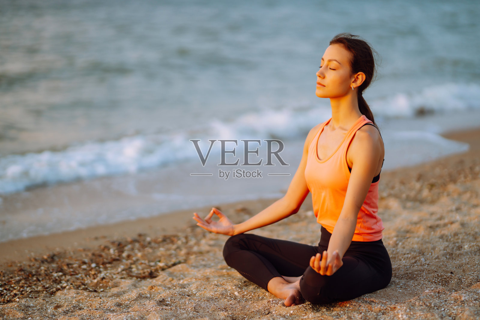 穿着运动服的年轻女子在海滩上做健身运动照片摄影图片