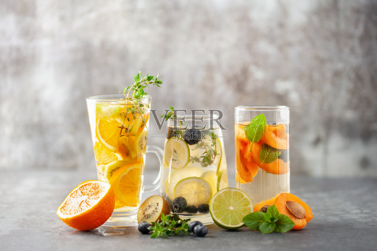 将排毒水倒入玻璃杯中。清爽夏日自制鸡尾酒,搭配水果、浆果和柑橘照片摄影图片