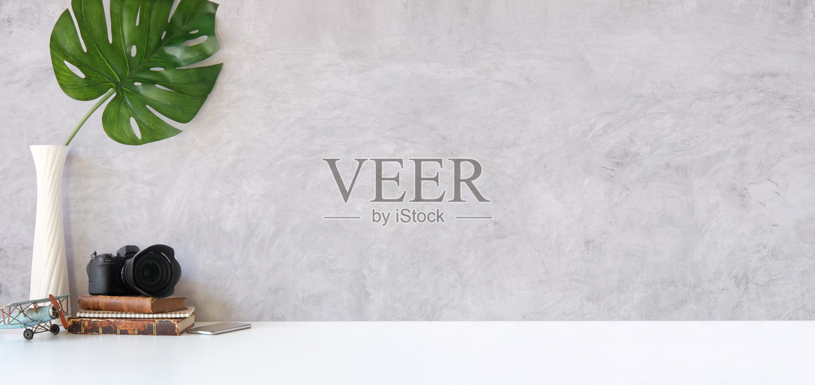 时尚的工作场所,相机,书和怪物叶在白色的桌子上。为你的文本复制空间。照片摄影图片