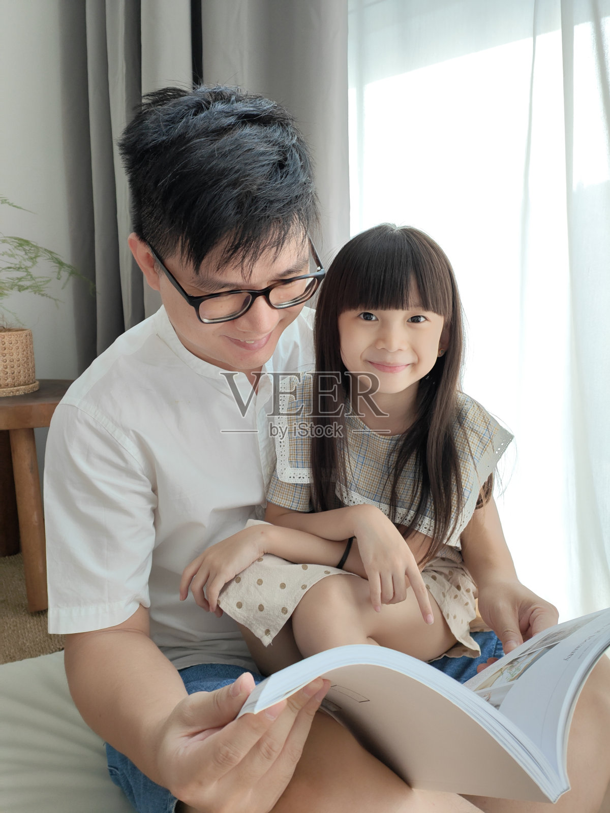 小亚洲女孩在家里和爸爸一起听爸爸讲童话照片摄影图片