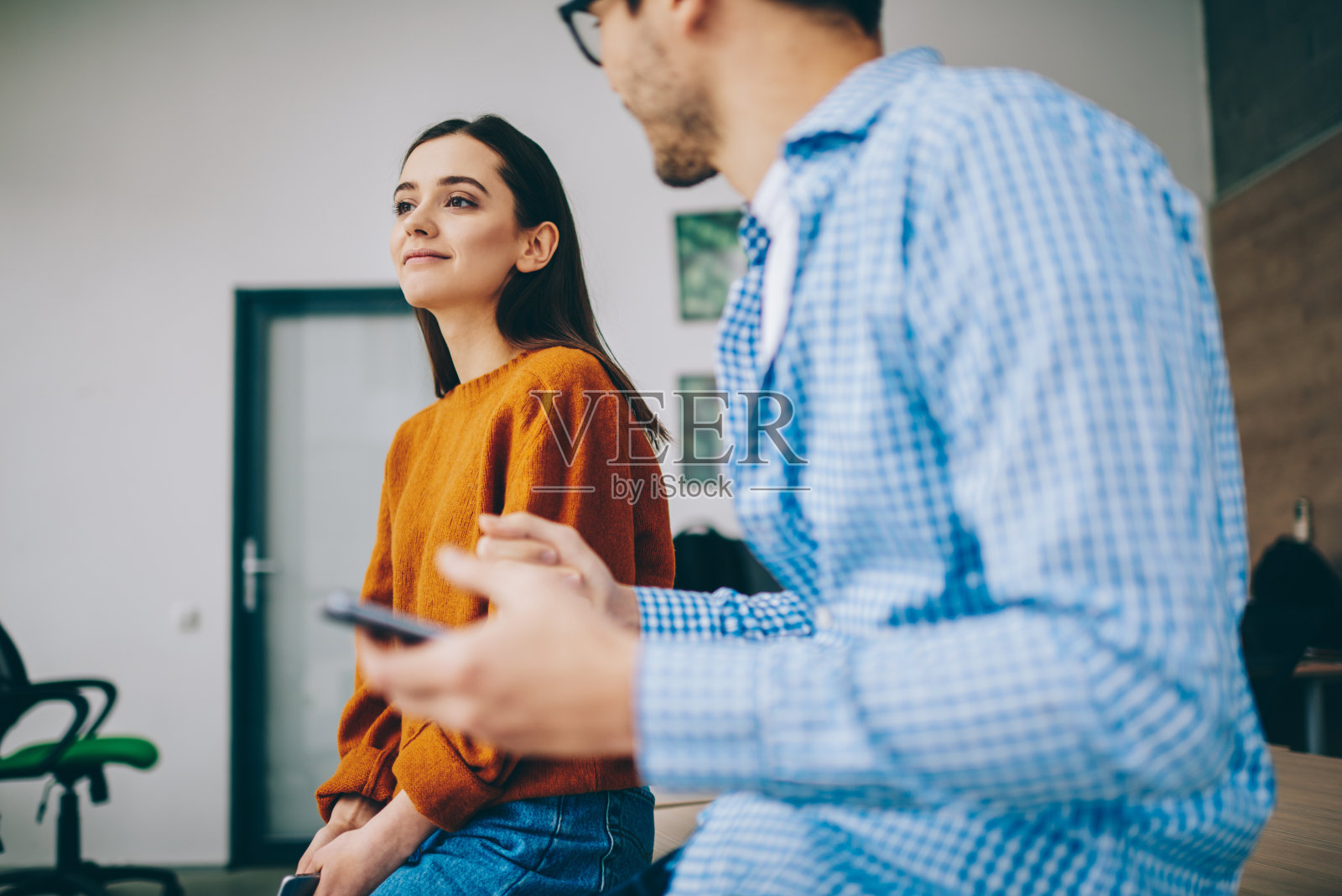 穿着休闲服装的白人男女同事在工作空间的休闲交流中讨论智能手机出版物,年轻的潮男享受现场交谈和友谊照片摄影图片