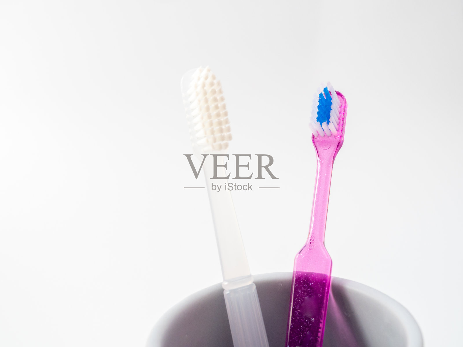 牙刷放在白色背景的杯子里照片摄影图片