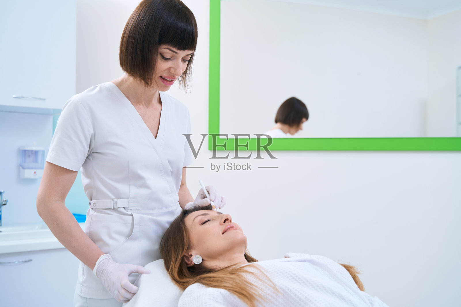 医生在病人脸上做注射标记照片摄影图片