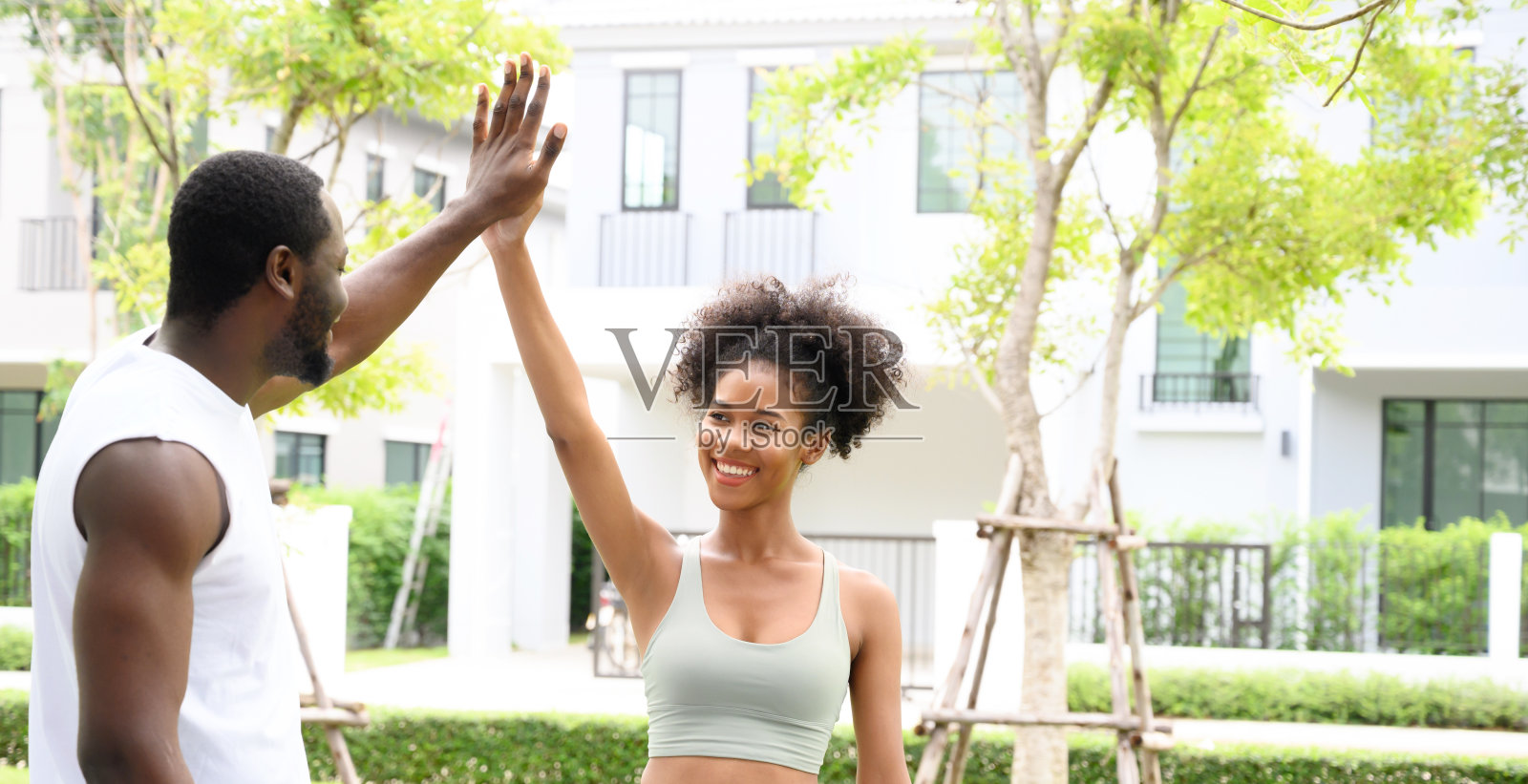 在户外训练成功后,一对年轻的非裔美国人健身夫妇站在公园里鼓掌。健身伙伴们击掌庆祝。健康的概念。照片摄影图片