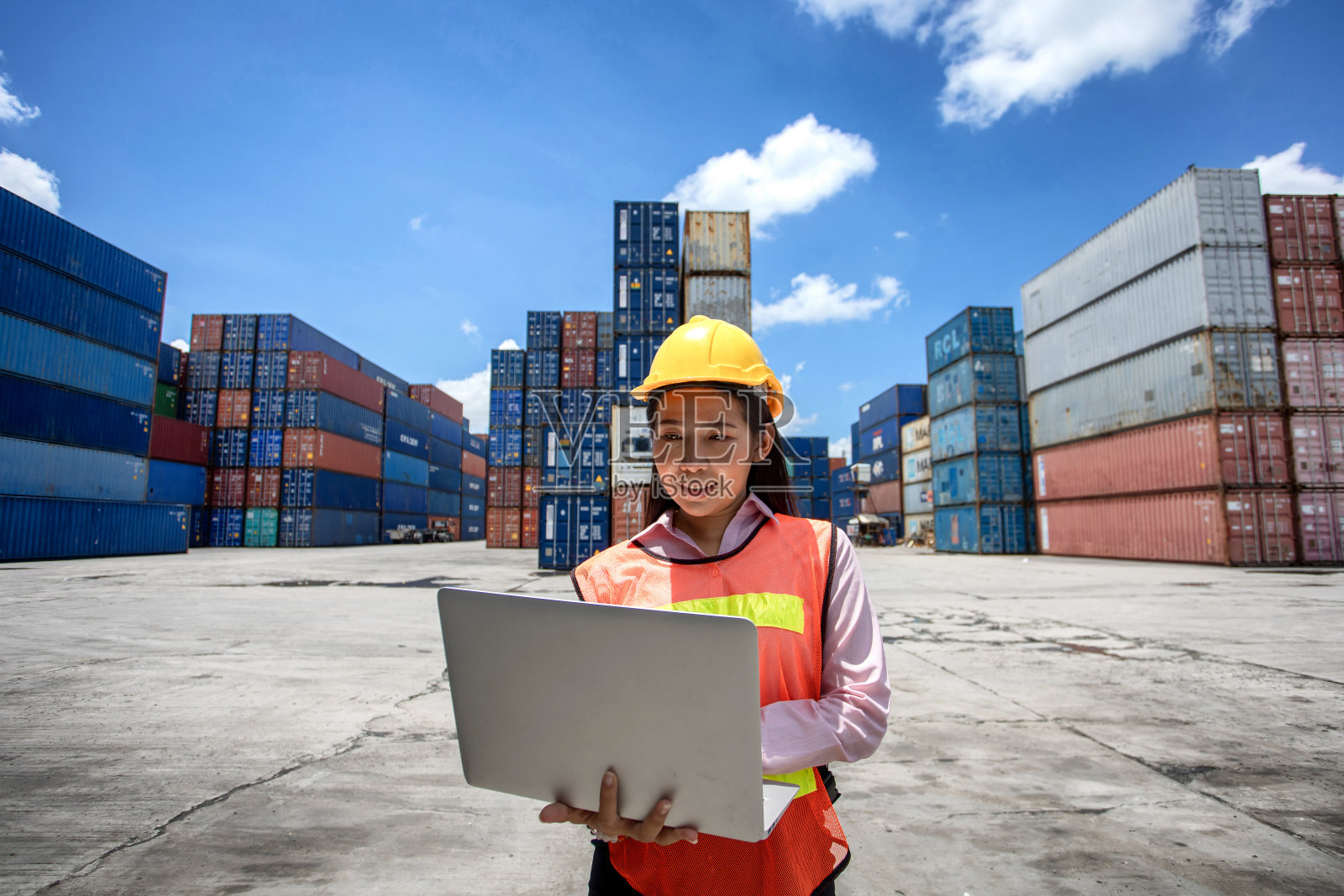 一个在集装箱里摆弄笔记本电脑的女人。从货运船上取集装箱,用于进出口。商务物流概念,进出口概念照片摄影图片