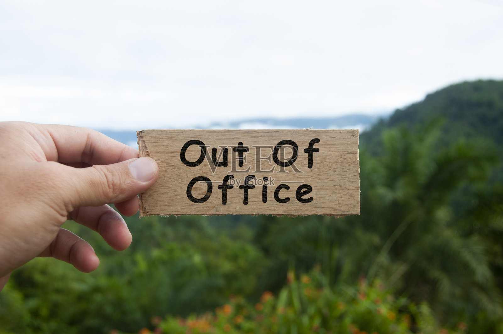 手持写有文字的木制横幅-离开办公室。有山和山的背景。照片摄影图片
