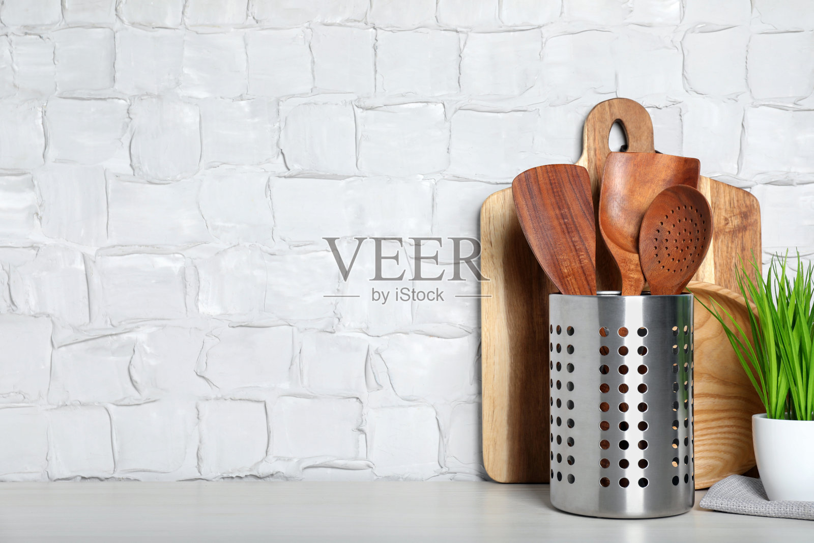 一套木制厨房用具,木板和室内植物在桌子上靠近白墙。空间的文本照片摄影图片
