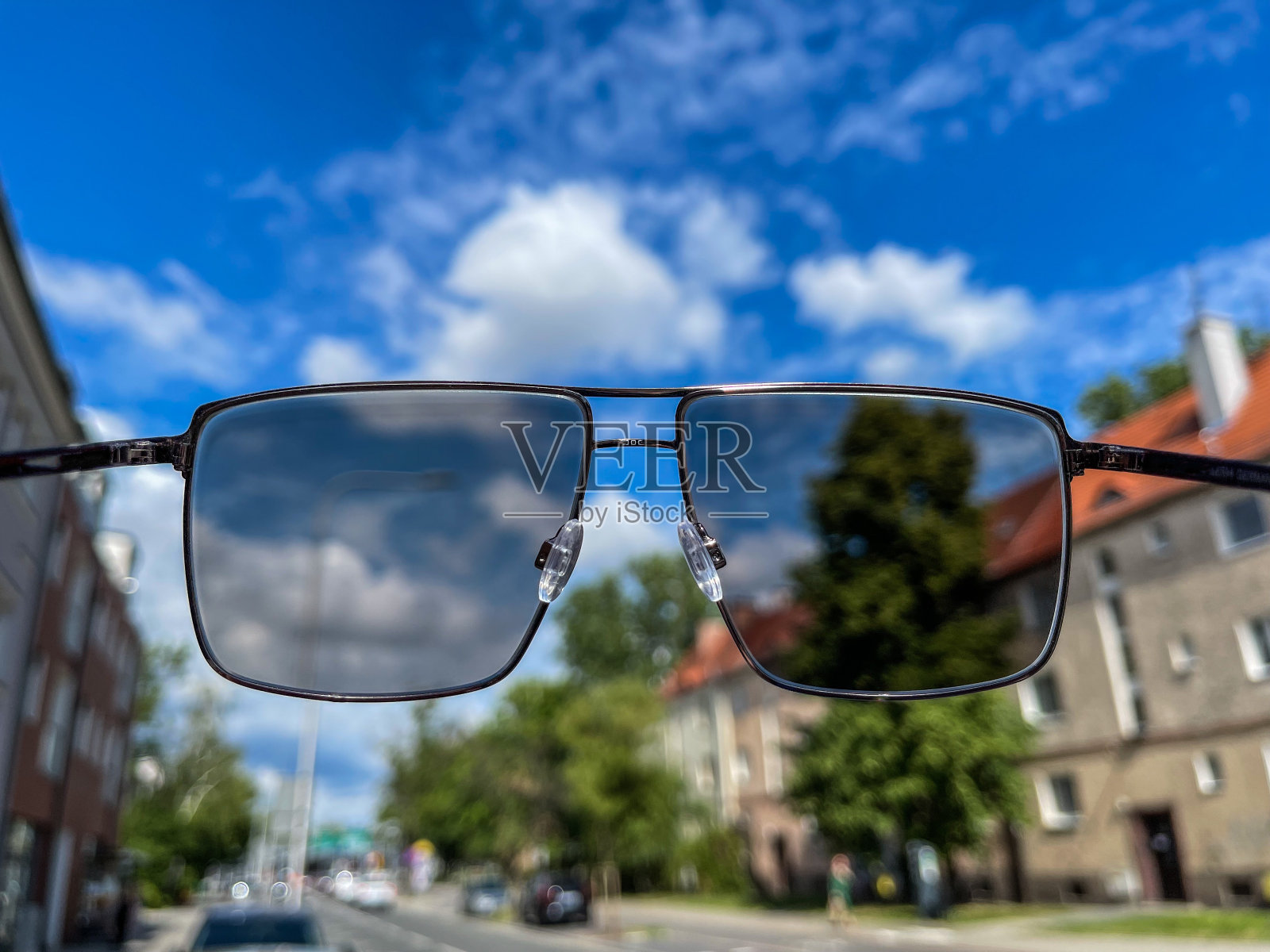 长方形金属灰色的太阳镜在夏季城市景观的背景上。照片摄影图片