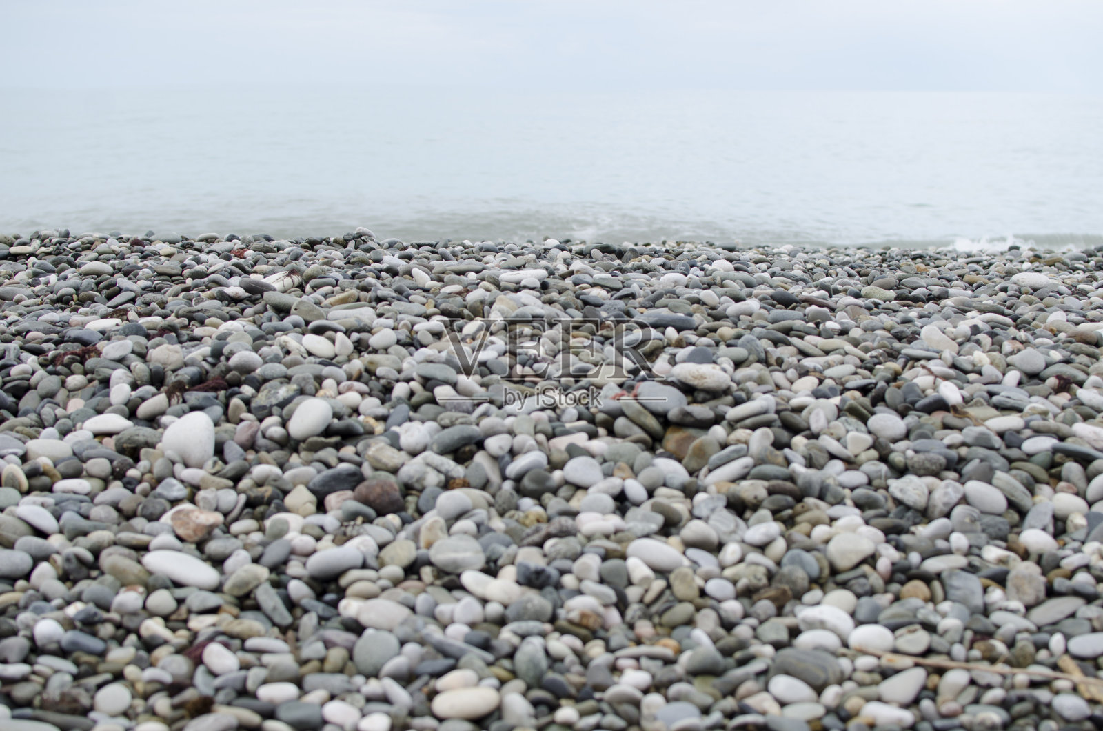 天空,大海和沙滩。美丽的海景,令人惊叹的鹅卵石海岸线。卵石海岸上的波浪。海泡石。冲浪。美丽的海滩。海岸线的特写照片摄影图片