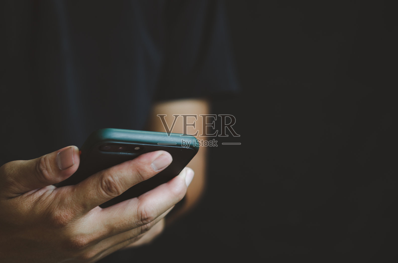 手持手机的人被隔离在黑色背景上。照片摄影图片