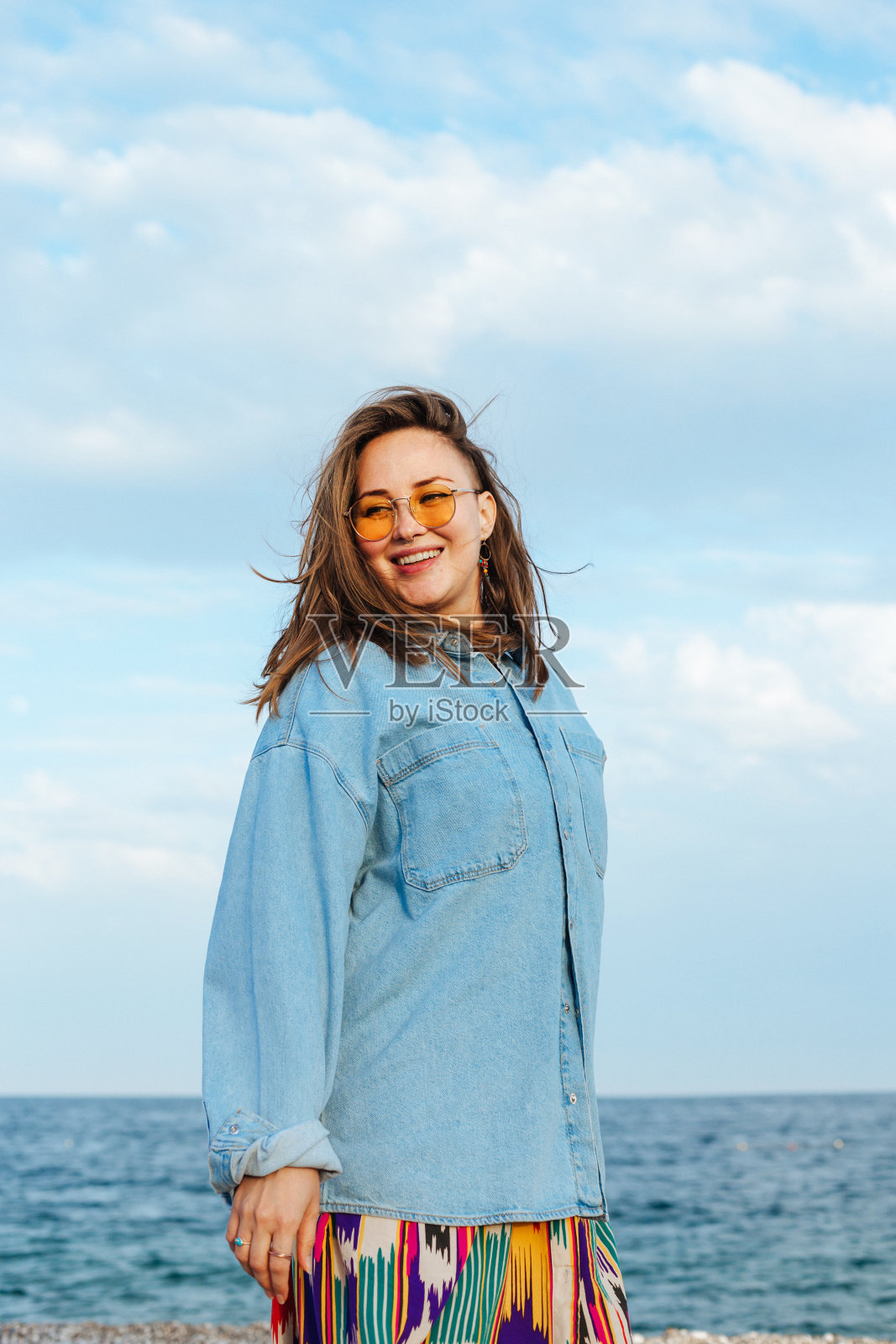 年轻多样的女人戴着黄色眼镜微笑,幸福。站在海边照片摄影图片