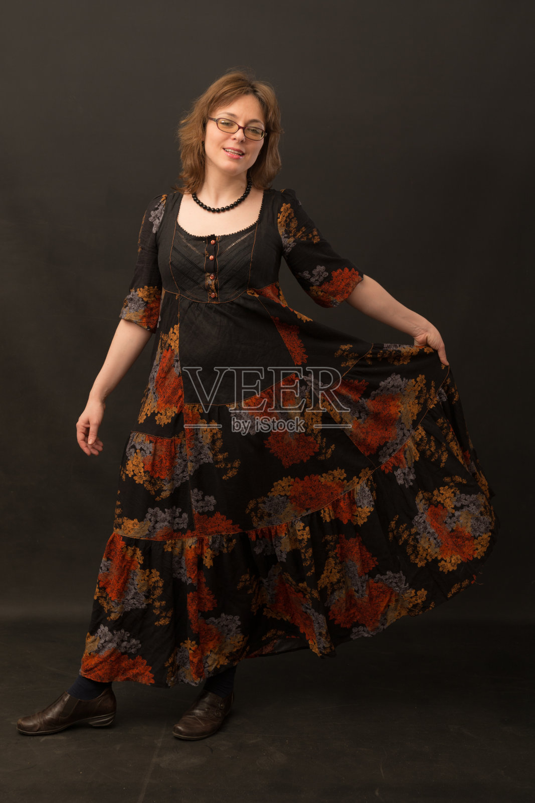 一个在黑色背景下穿着长裙的女人照片摄影图片