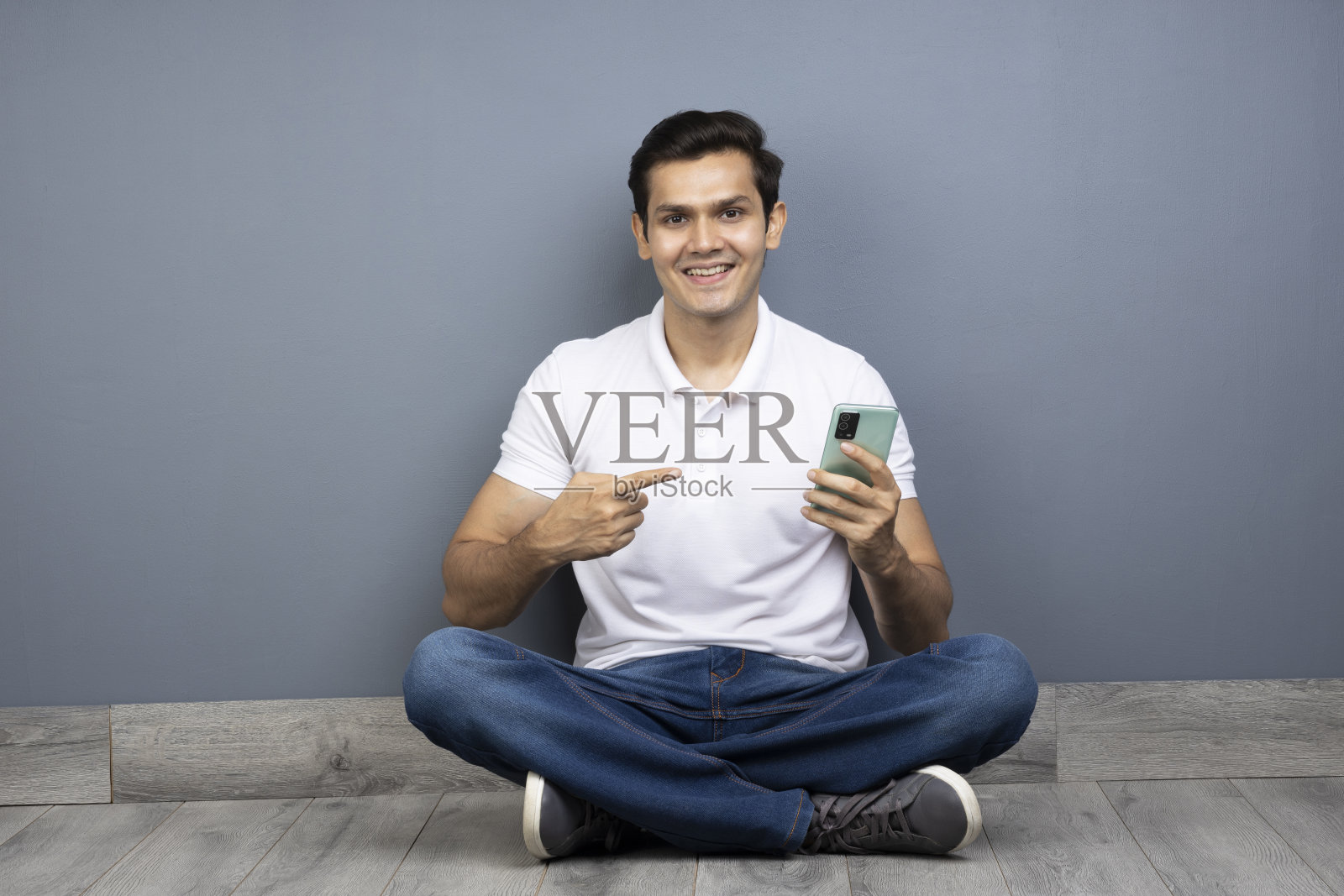 坐在地板上用手机的男人跷着腿,库存照片照片摄影图片