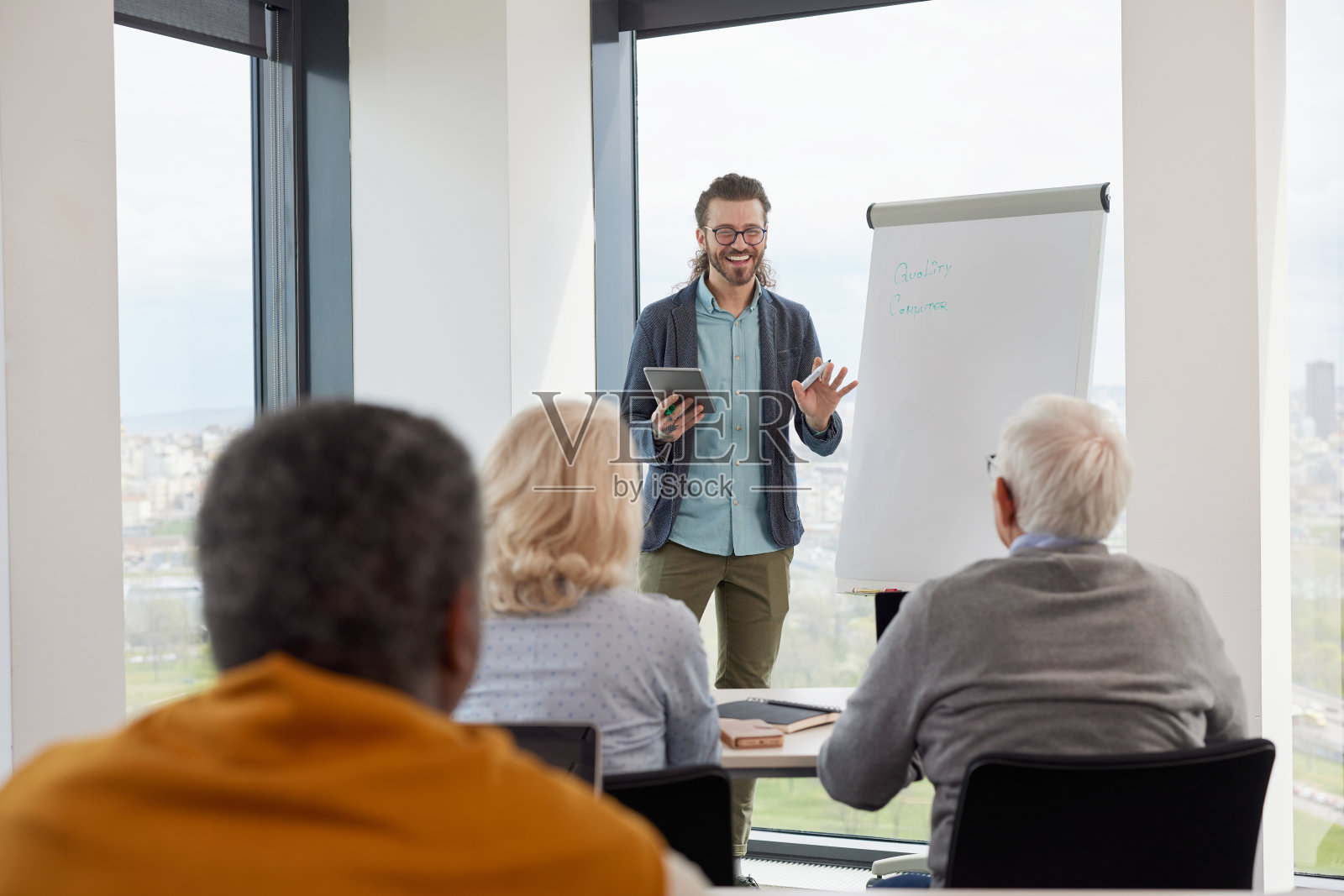 一位教授正在教室里向高年级学生展示平板电脑上的课程。照片摄影图片