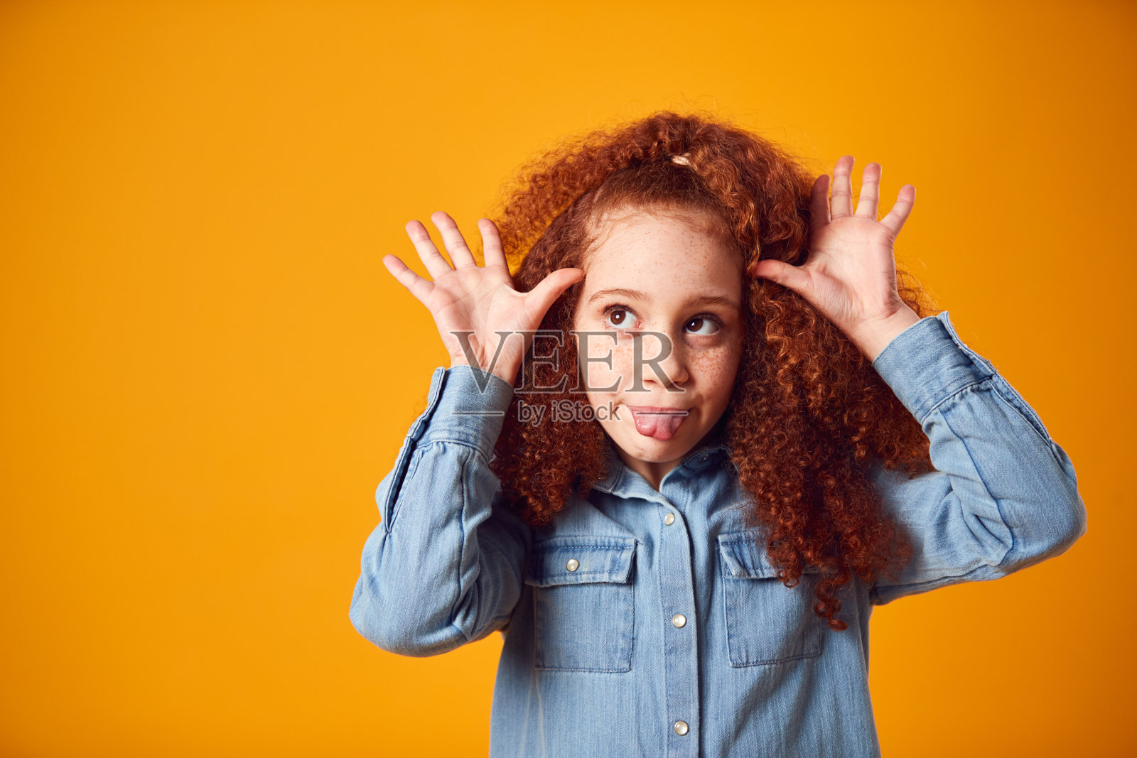 工作室肖像微笑的年轻女孩拉滑稽的脸拍摄对黄色的背景照片摄影图片