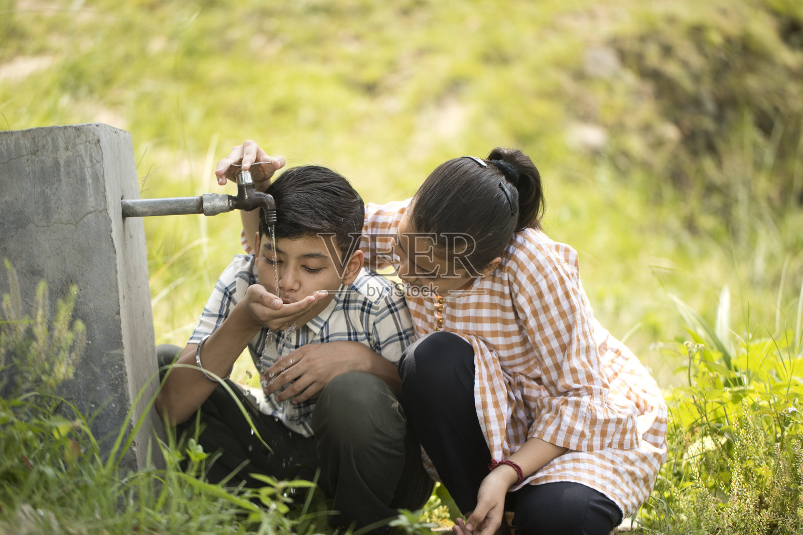 农村男孩和女孩喝自来水照片摄影图片