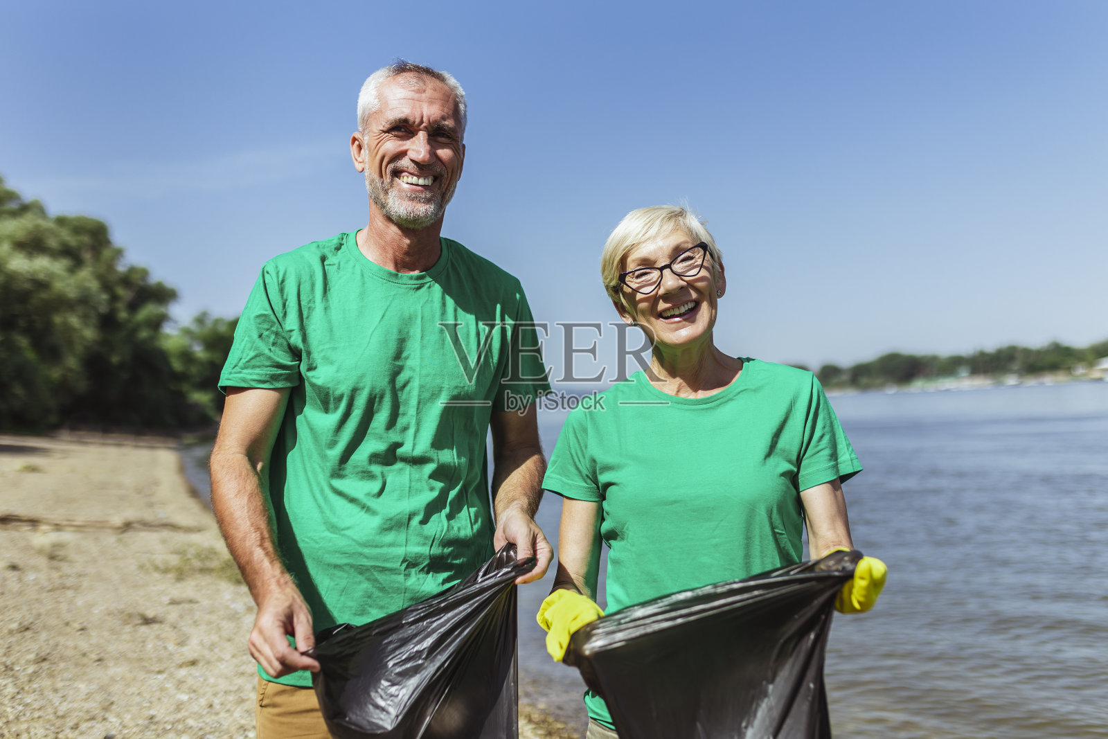 老年志愿者在河边捡垃圾照片摄影图片