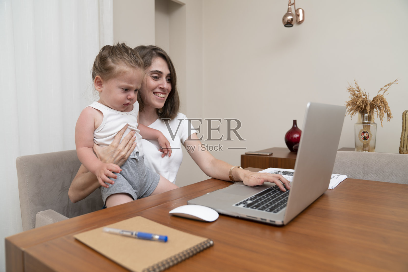 带着小女儿在家工作的女人。照片摄影图片